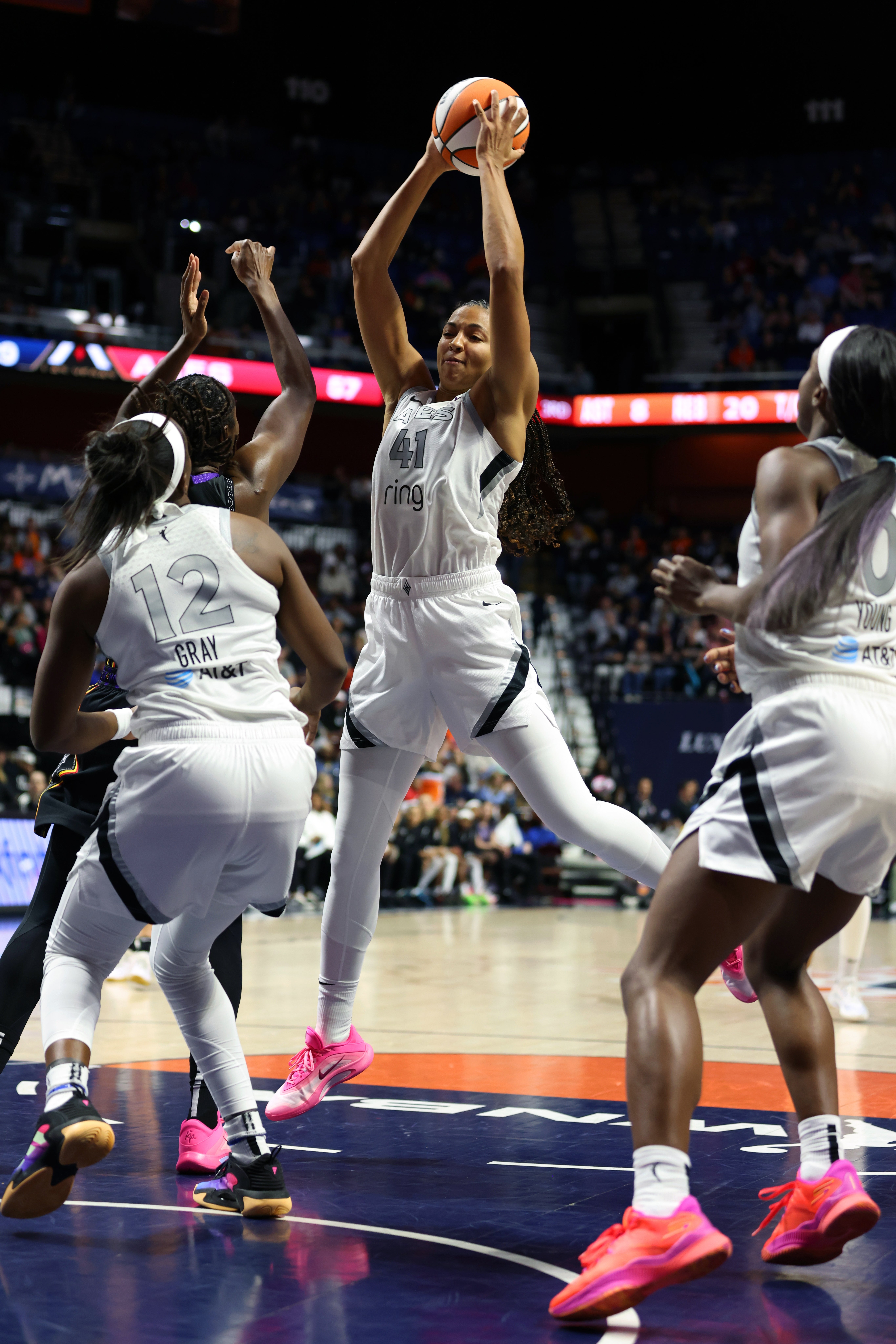 Basketball subordinate    successful  mid-air, wearing a achromatic  jersey, prepares to marque   a changeable  during a game, portion    opponents situation   her connected  the court