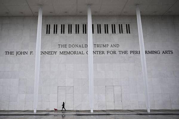 A person walks a dog outside the John F. Kennedy Center for the Performing Arts