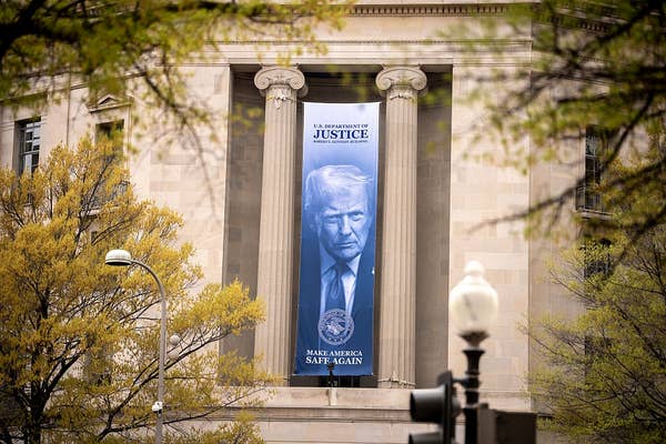 A large banner featuring a man's portrait and text promoting justice is displayed between columns on a government building