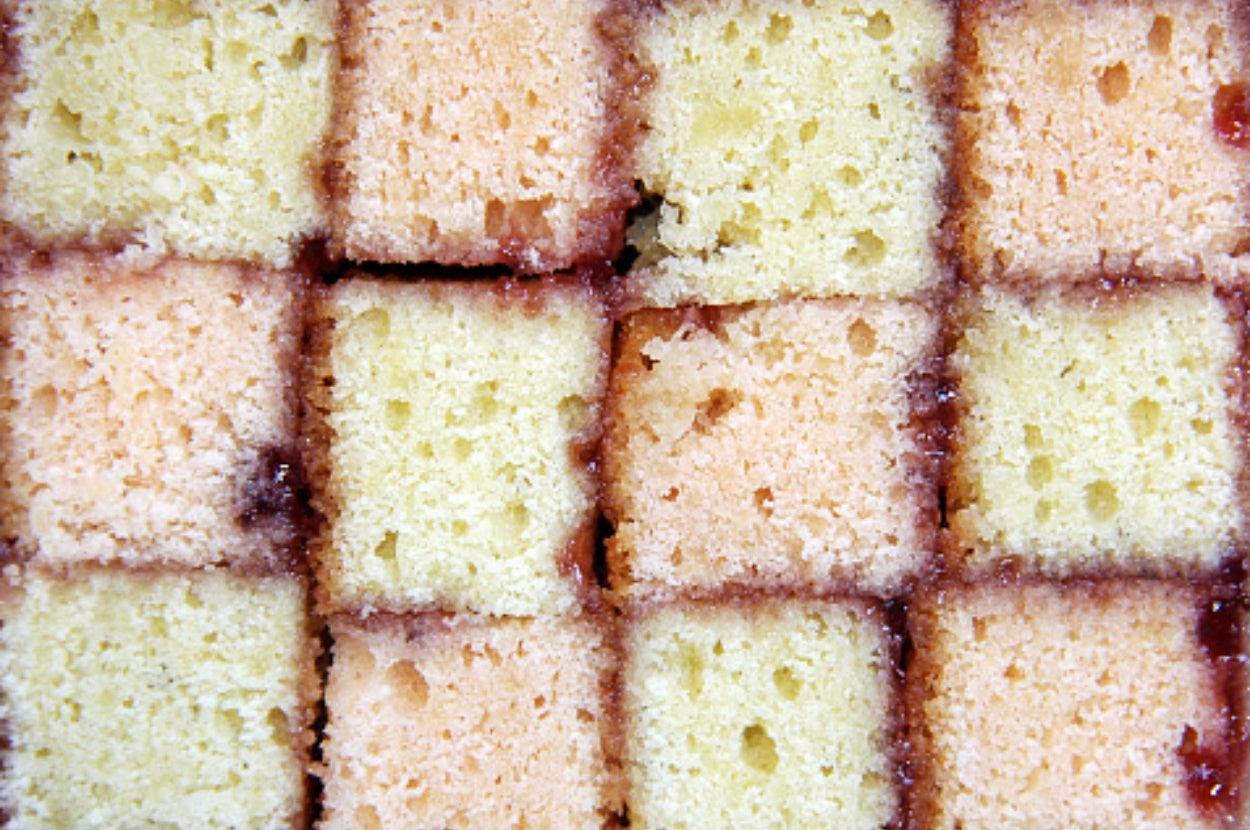 Close-up of a Battenberg cake showing its iconic checkerboard pattern of sponge squares divided by a layer of jam