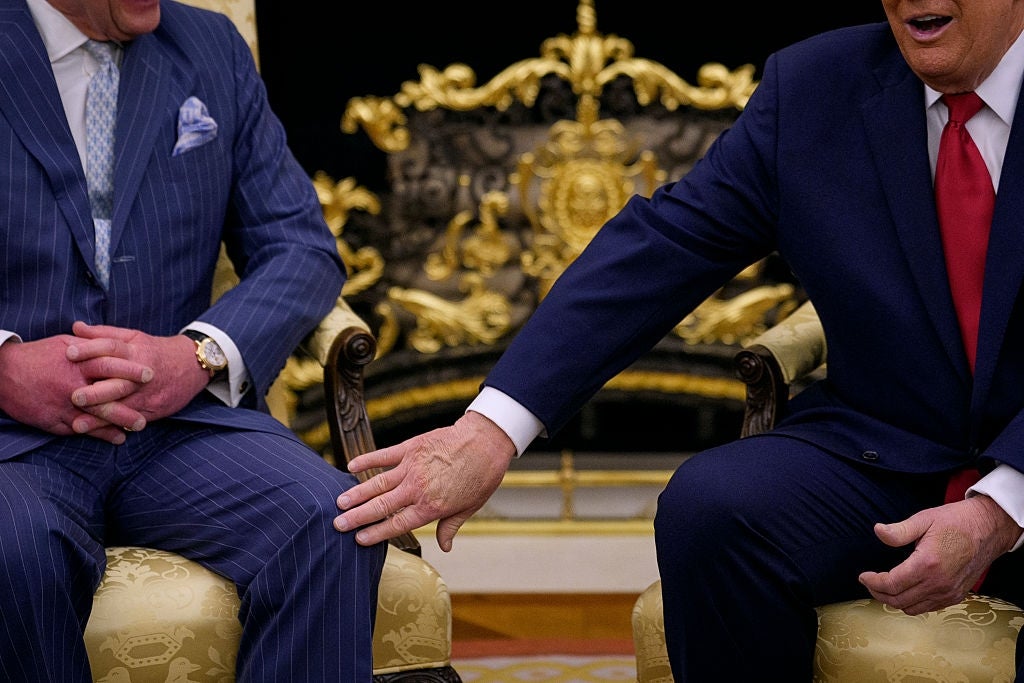 Two men beryllium   successful  ornate chairs. One antheral   gestures, extending a manus  towards the other's knee. Both are successful  ceremonial  suits, seated successful  a lavish setting