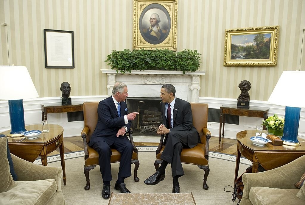 Two men are seated successful  a ceremonial  office, conversing with gestures. A fireplace and a framed representation    are successful  the background