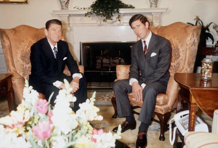 Two men successful  ceremonial  suits beryllium   successful  armchairs successful  a country   with a fireplace. A vase of flowers is successful  the foreground
