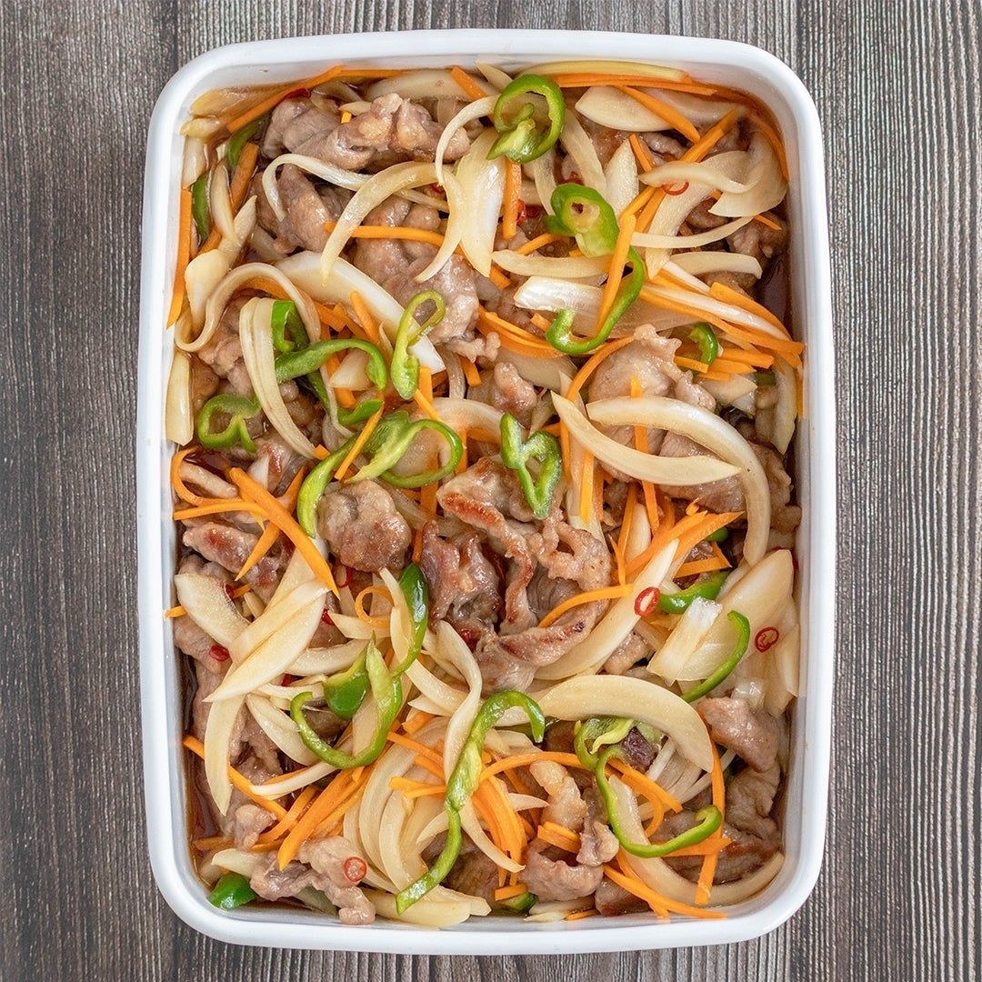 玉ねぎ、にんじん、ピーマンと炒めた肉料理が白い皿に盛り付けられています。
