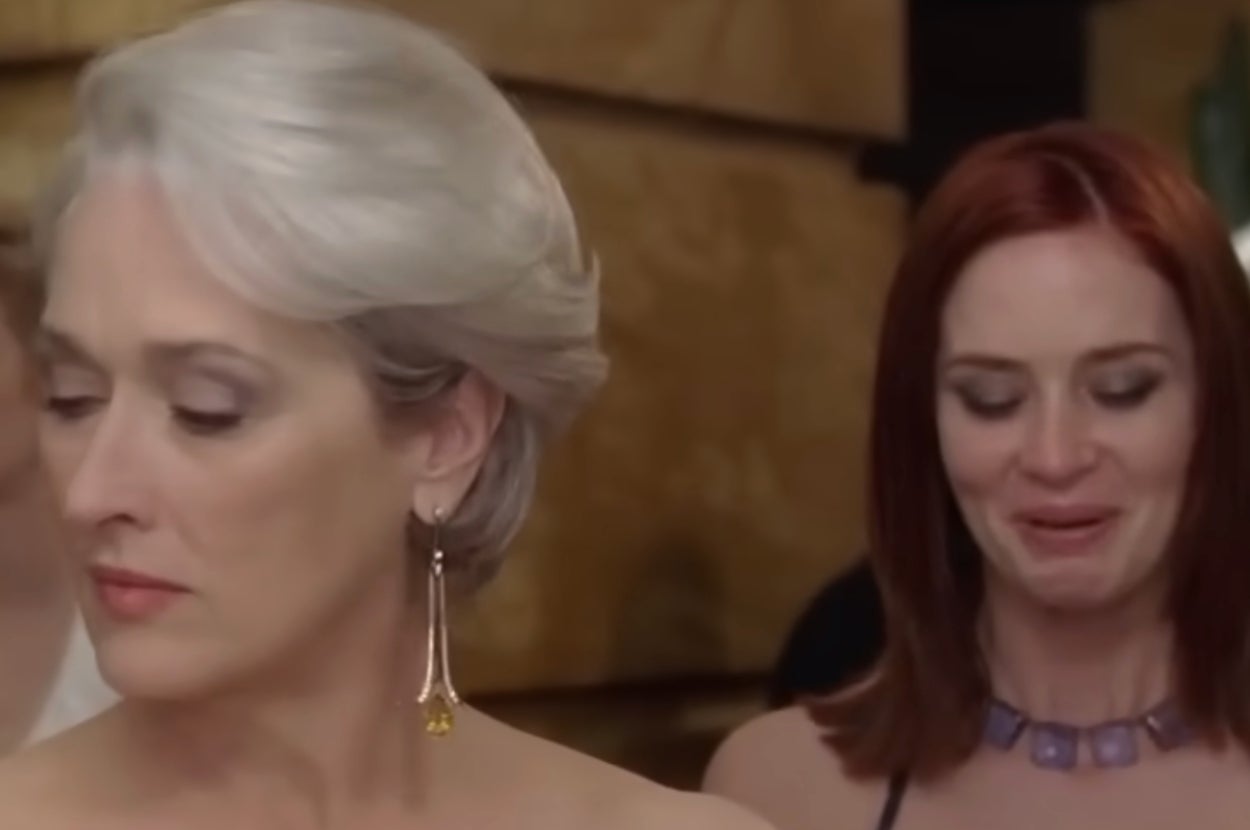 Two women in formal attire; one with short hair and dangling earrings looks aside, the other with long hair appears emotional
