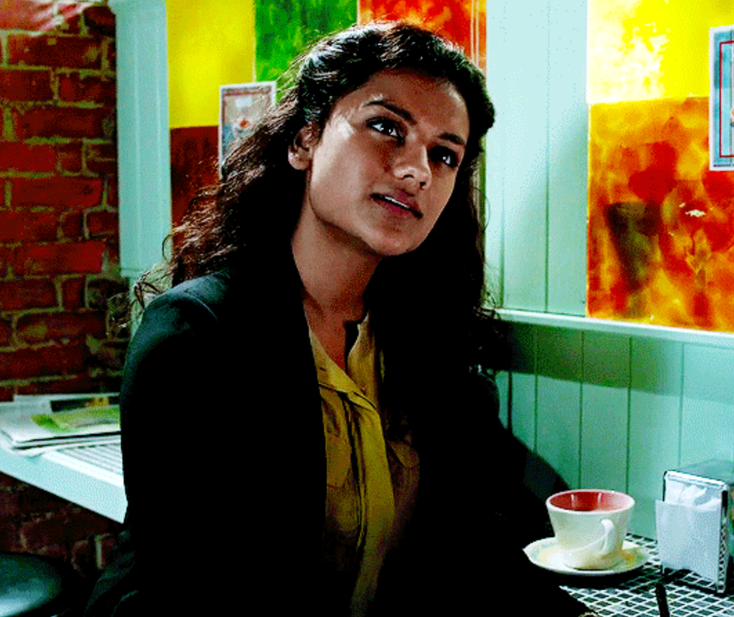 Young pistillate   sitting successful  a cafe, wearing a blazer implicit    a blouse, with a thoughtful look  adjacent  to a beverage  cupful  connected  the table