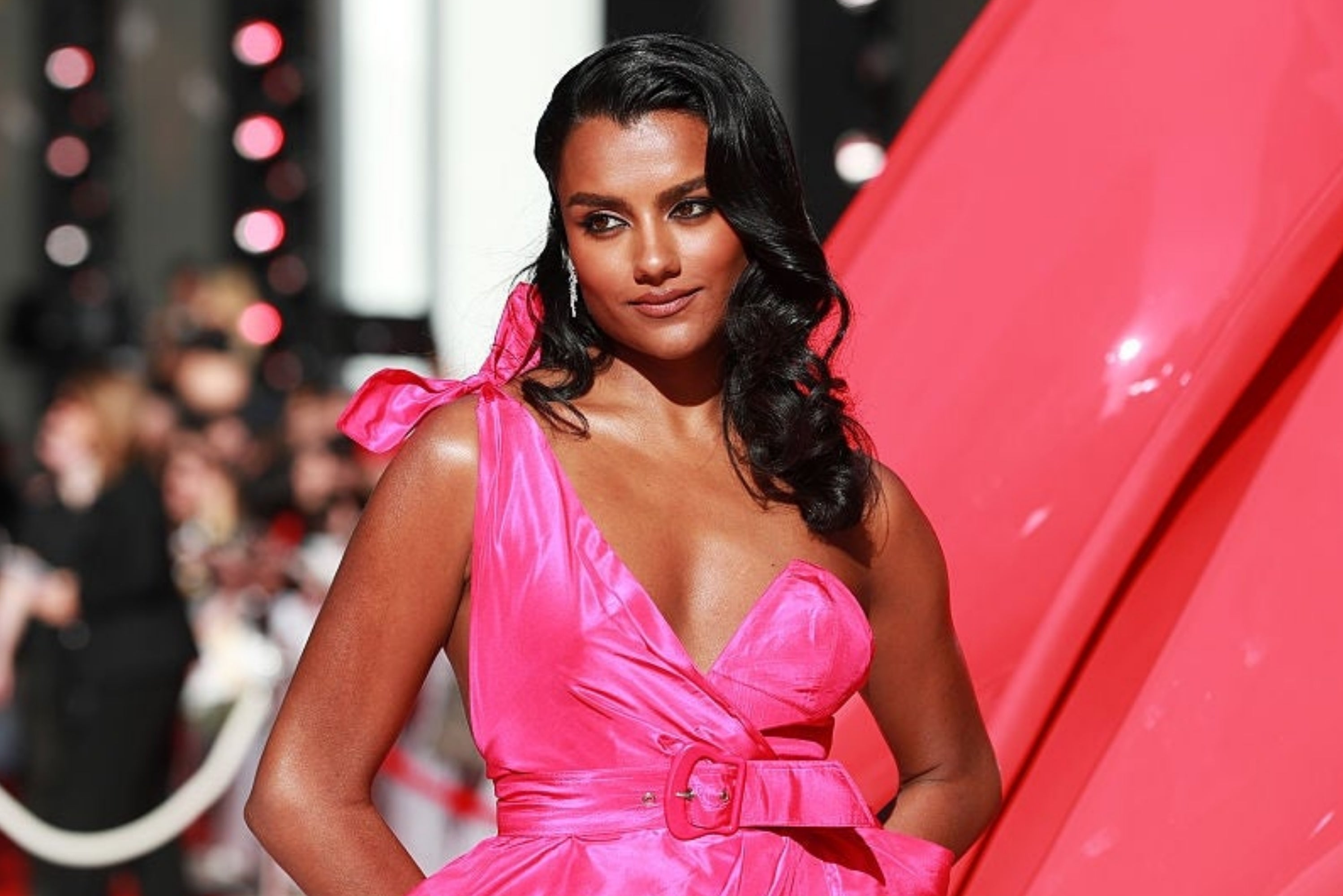 Woman successful  stylish, sleeveless gown poses connected  a reddish  carpet with a assured  expression