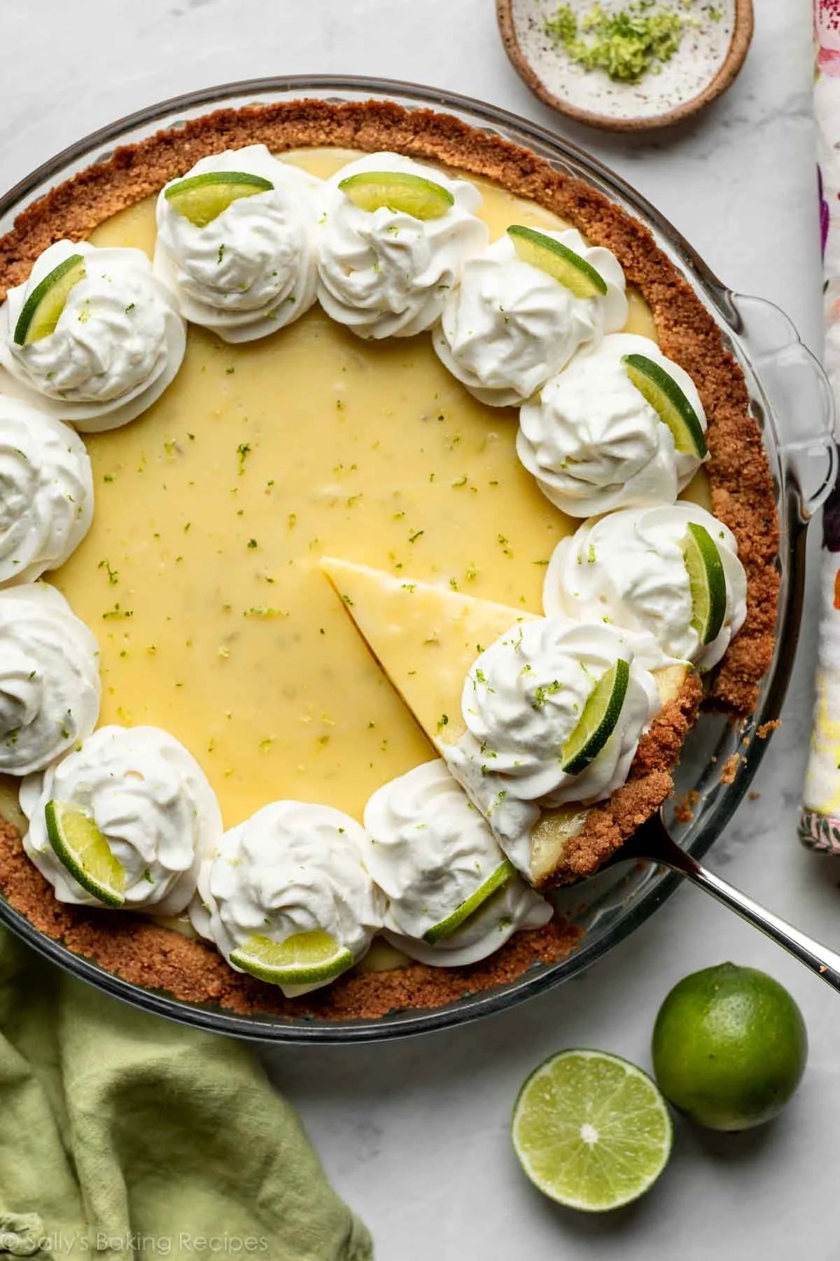 Key lime pastry  with whipped pick  dollops, lime slices, and a portion    somewhat  removed, connected  a array  with garnishes