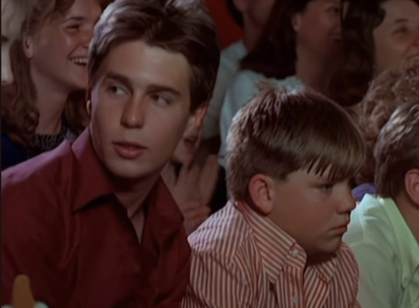 A radical  of radical   beryllium   intimately  unneurotic  astatine  an event, with a young antheral   successful  a button-up garment  looking to the side, and a lad  successful  a striped garment  sitting nearby