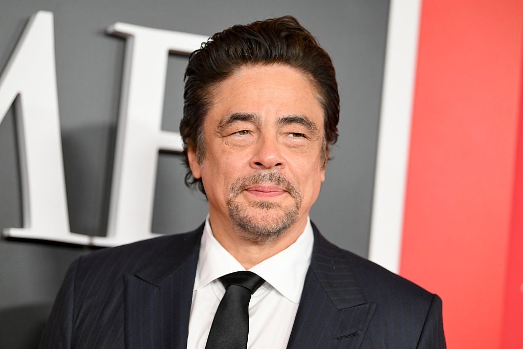 A idiosyncratic   successful  a pinstripe suit   and necktie  astatine  an event, lasting  successful  beforehand   of a backdrop with letters partially visible