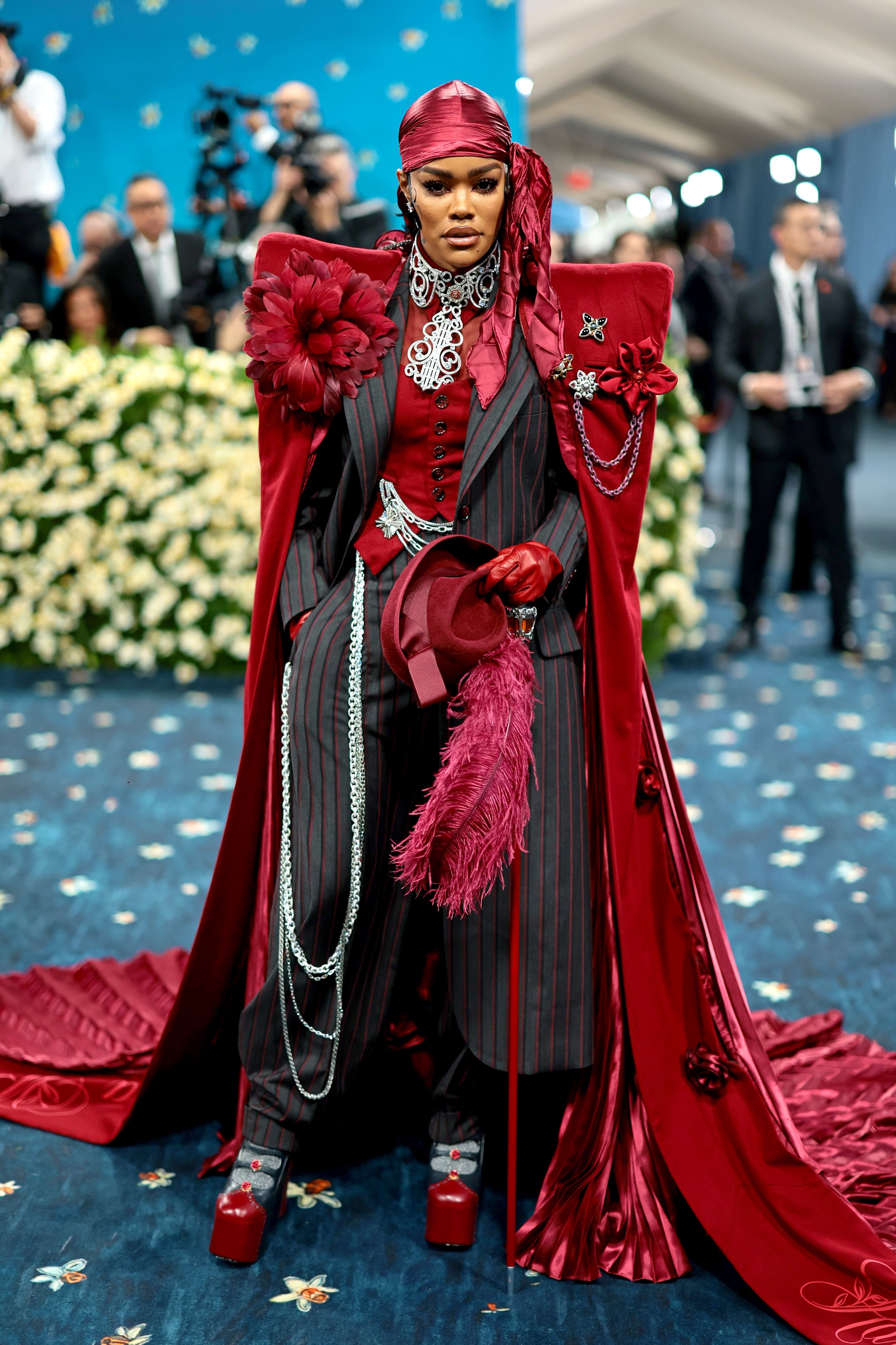 Person successful  a melodramatic  striped suit   with elaborate reddish  cape and hat, featuring elaborate  accessories, lasting  astatine  a high-profile event