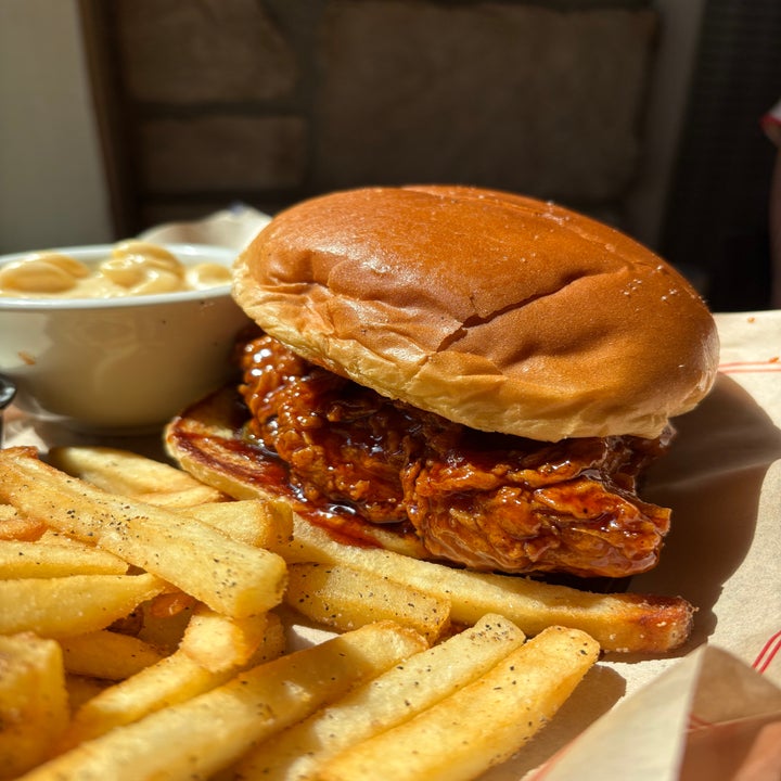 Chicken sandwich with barbecue sauce, served with seasoned fries and a side of macaroni and cheese