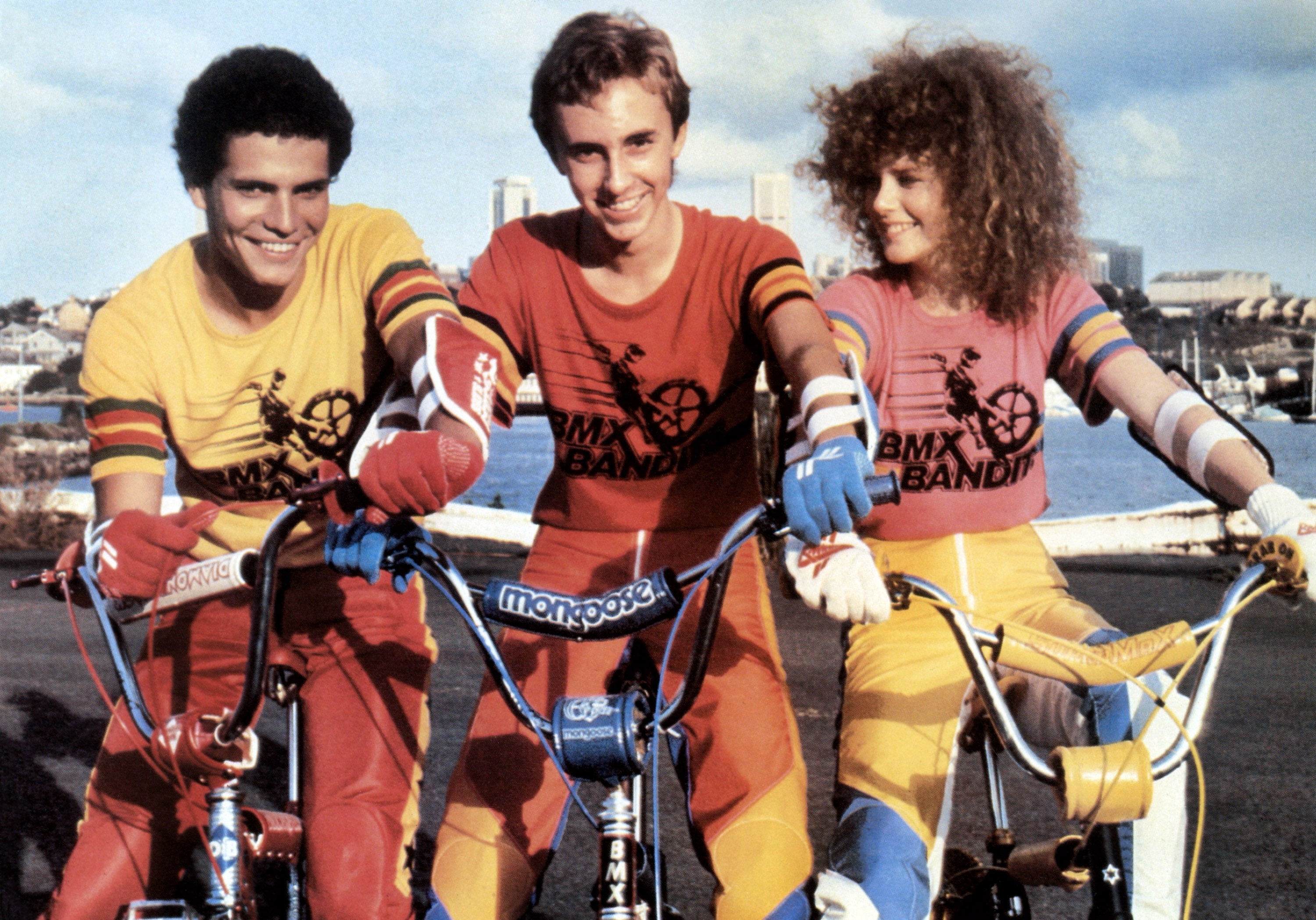 Three radical   successful  matching BMX Bandit outfits with BMX bikes, smiling and posing outdoors