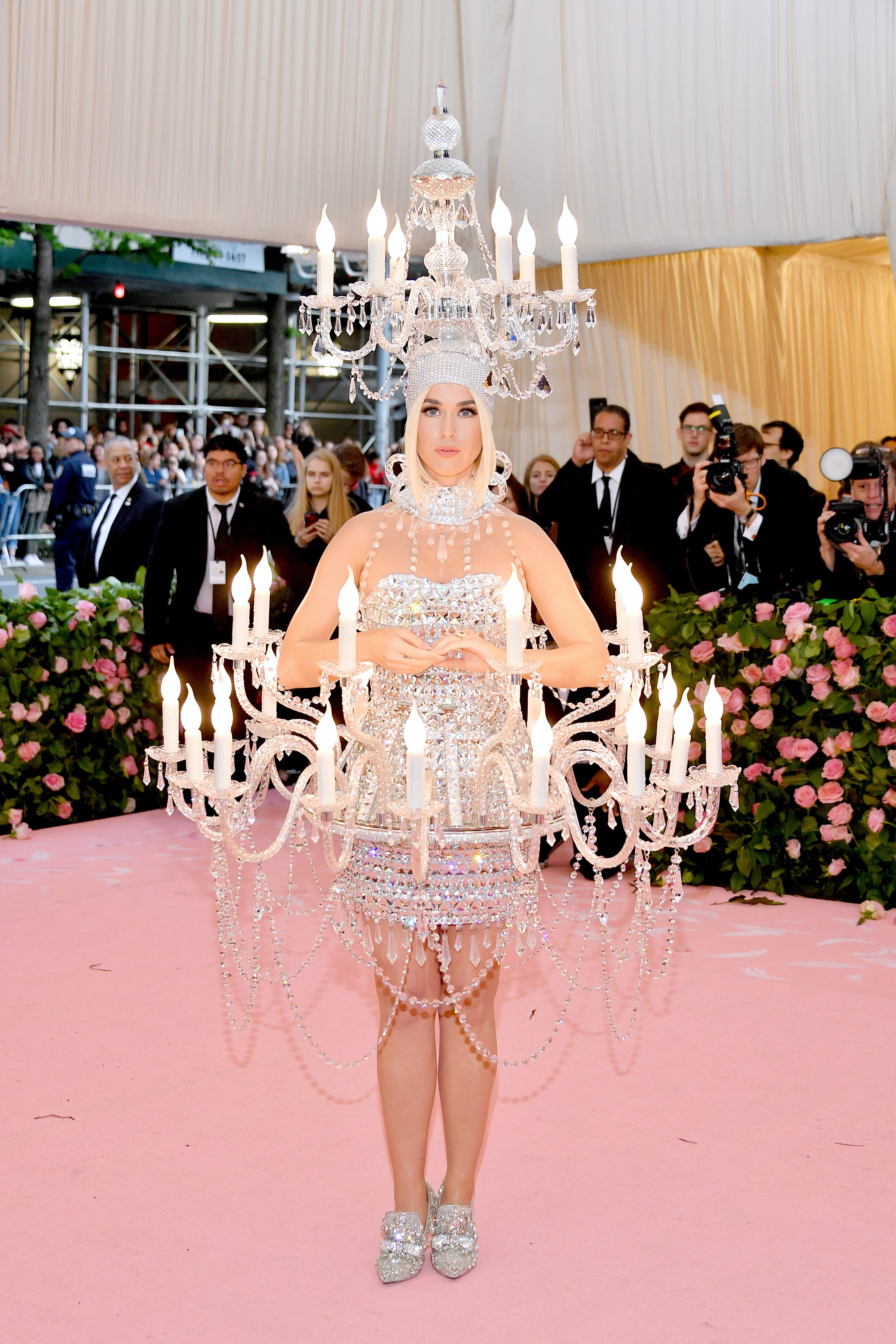 Person successful  chandelier-inspired outfit with crystal details and headpiece astatine  a manner  event, surrounded by onlookers and photographers
