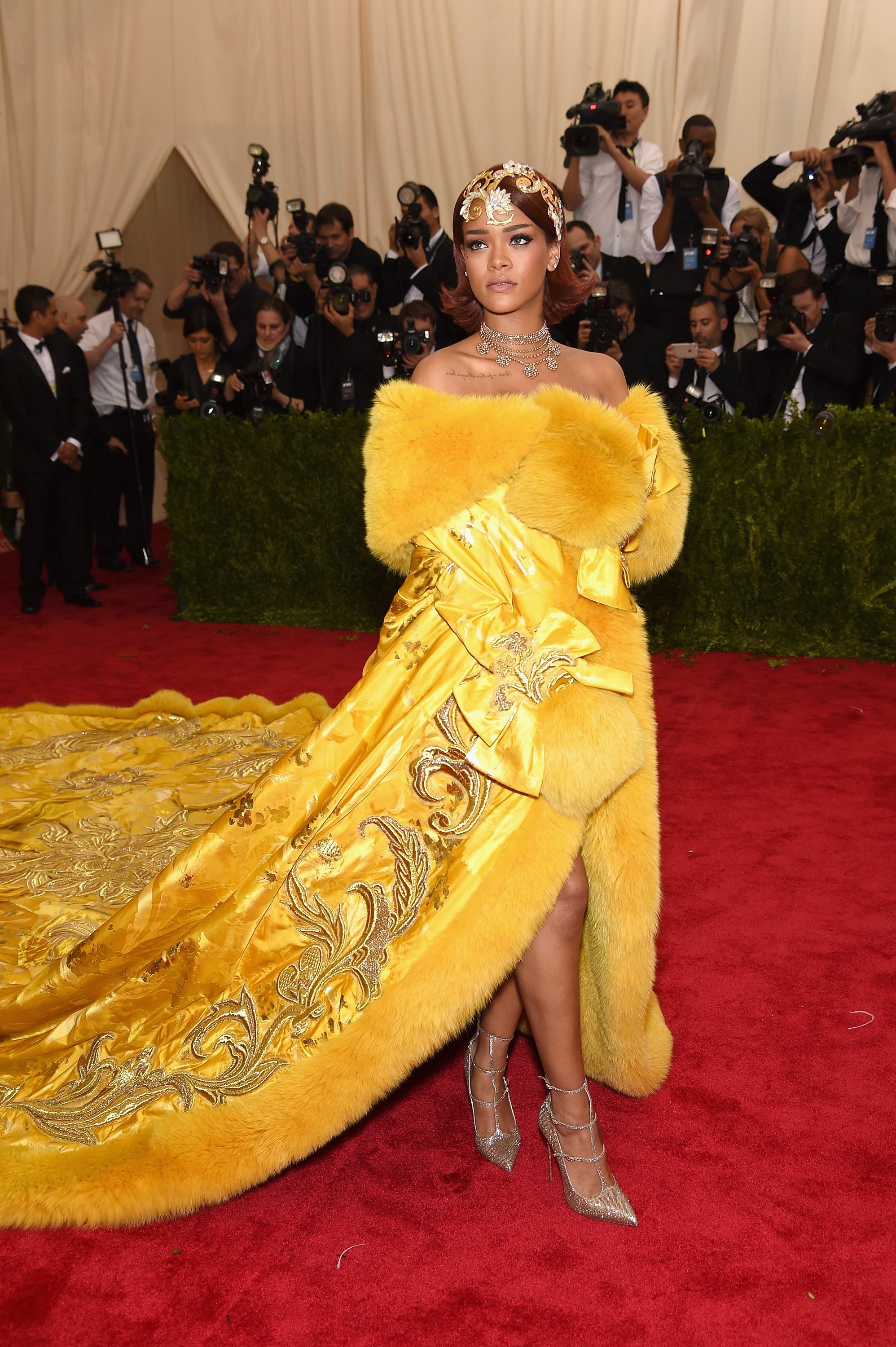 A personage  successful  an ornate gown with a agelong  bid     poses connected  the reddish  carpet, surrounded by photographers
