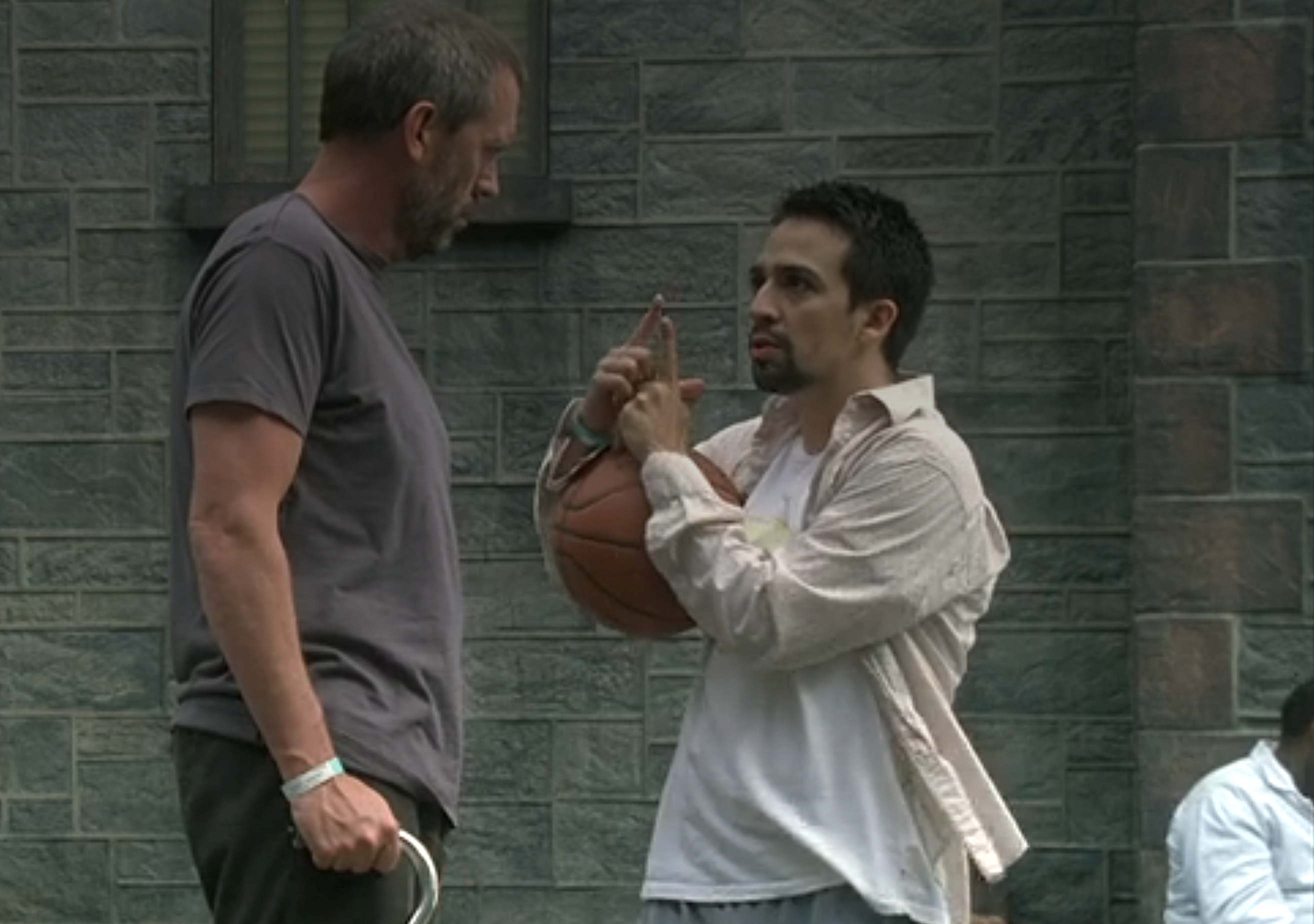 Two men person  a conversation; 1  is holding a hoops  and gesturing with his hands. They look  to beryllium  engaged successful  a superior   discussion