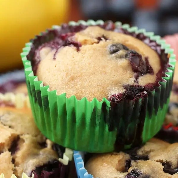 Blueberry muffin in a green paper liner, surrounded by other muffins