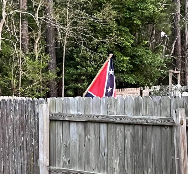 Reddit post showing a confederate flag on a fence, captioned "My neighbor moved her confederate flag a little too close to our fence line."