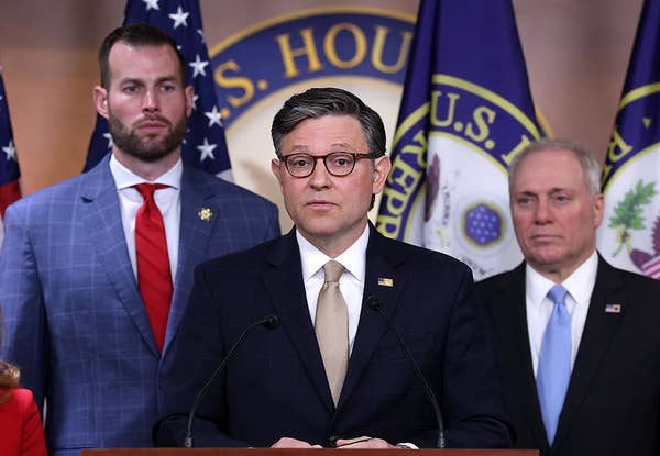 Three men in suits stand at a podium with U.S. flags and "U.S. House of Representatives" signage behind them during a press conference