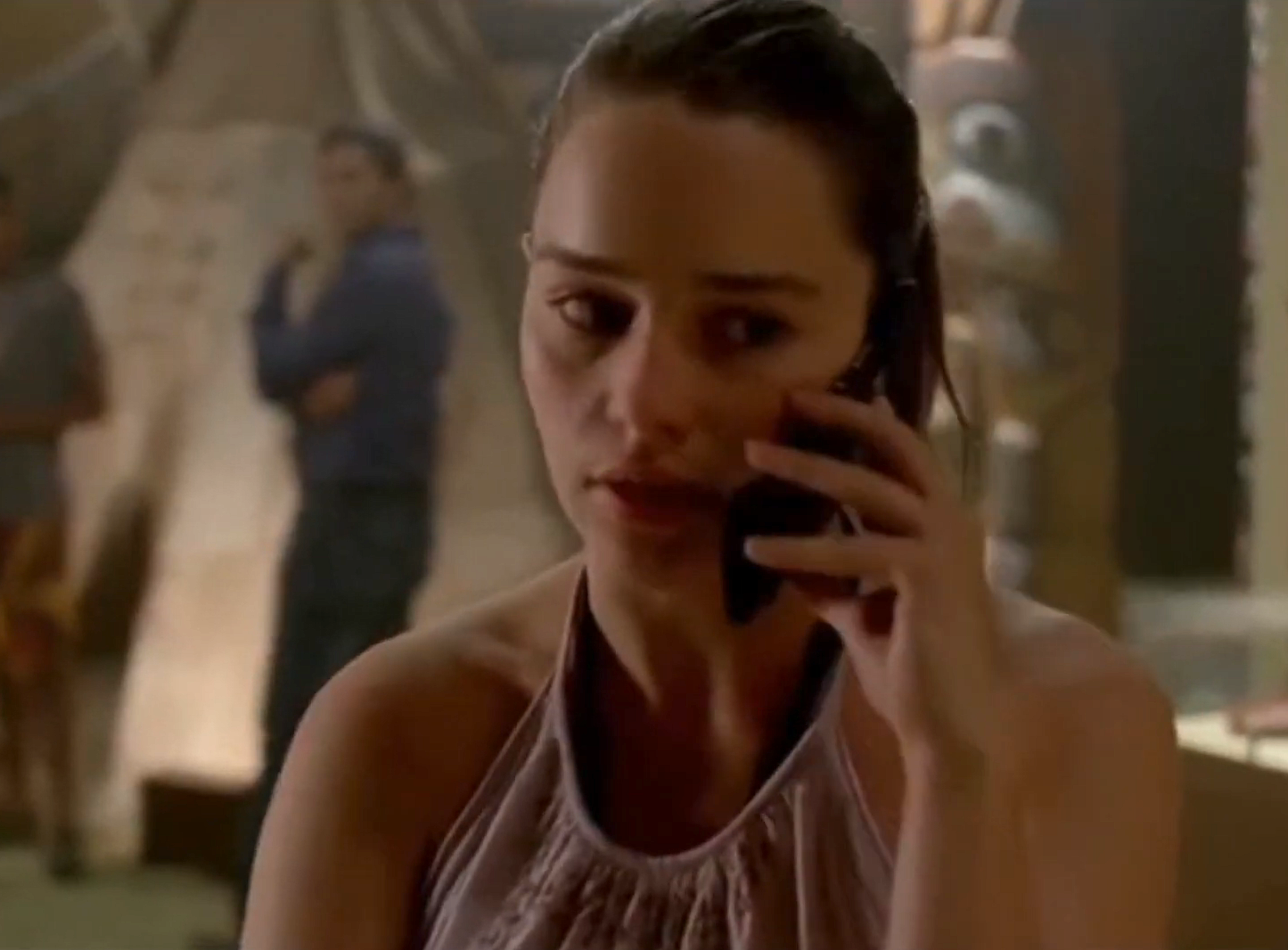 A idiosyncratic   is talking connected  a mobile phone, wearing a sleeveless top, successful  an indoor setting