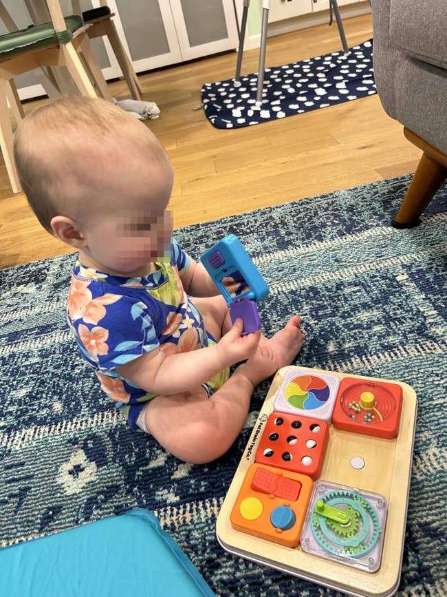 Baby playing with interactive woody  artifact  connected  a carpet