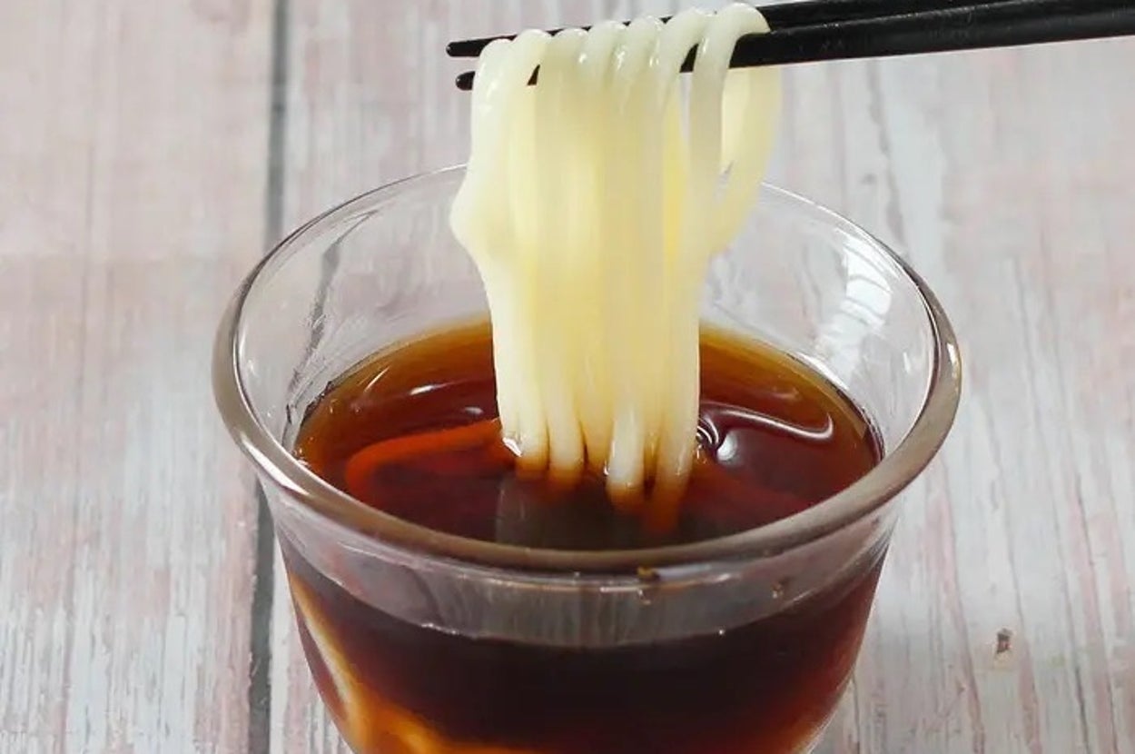 ガラスの器に入ったつゆに麺を箸で浸している様子。