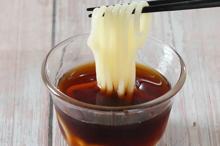 ガラスの器に入ったつゆに麺を箸で浸している様子。