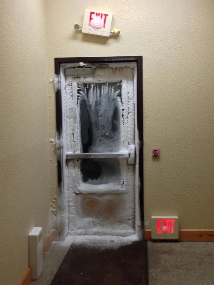 Frozen doorway  with crystal  buildup wrong  a building; 2  "EXIT" signs supra  and below