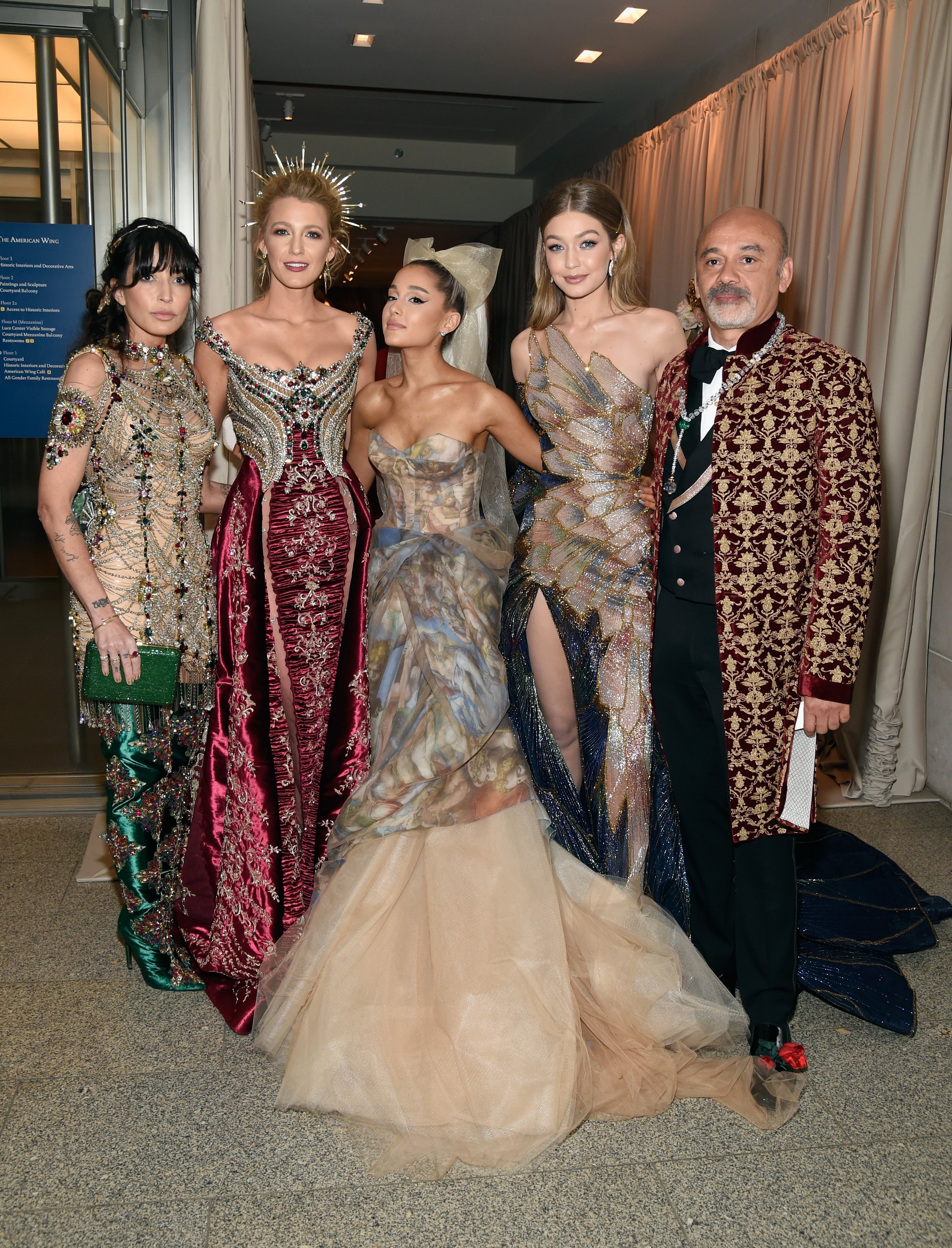 Group of 5  connected  a reddish  carpet, dressed successful  elegant and ornate evening gowns and a patterned suit