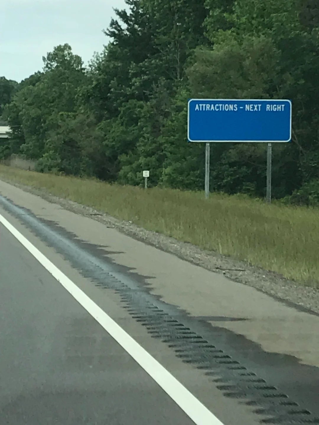 Roadside motion   reads "Attractions - Next Right" with trees successful  the background