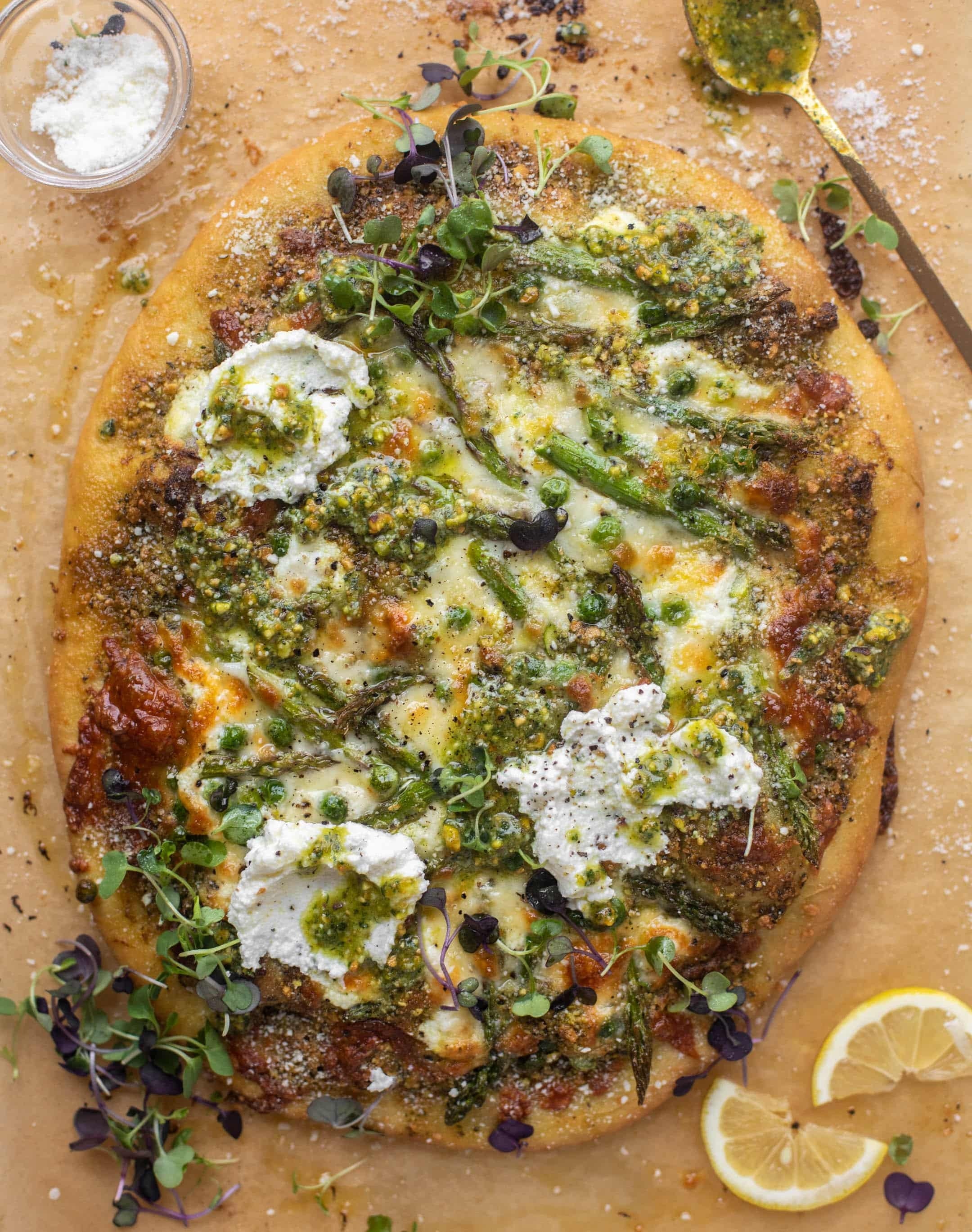 Delicious homemade pizza topped with ricotta, microgreens, pesto, and lemon slices
