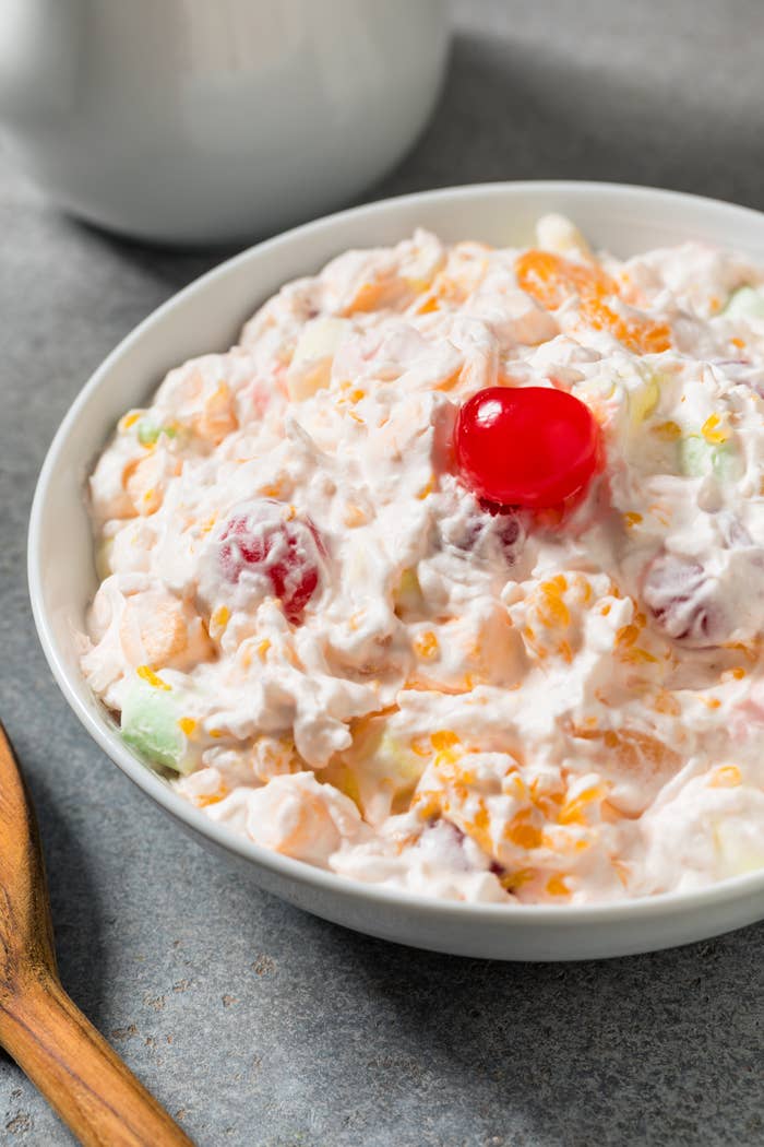 Fruit salad with creamy dressing in a bowl, topped with a cherry