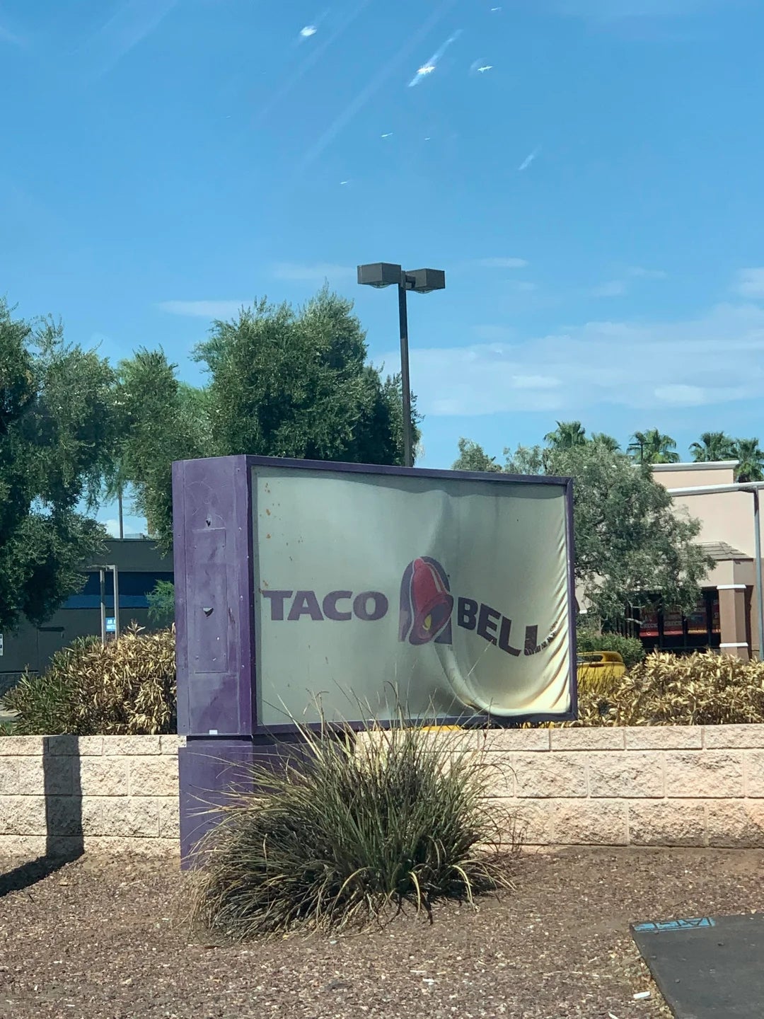 Taco Bell motion   successful  beforehand   of a restaurant, partially peeled and weathered, with greenery and a gathering  successful  the background