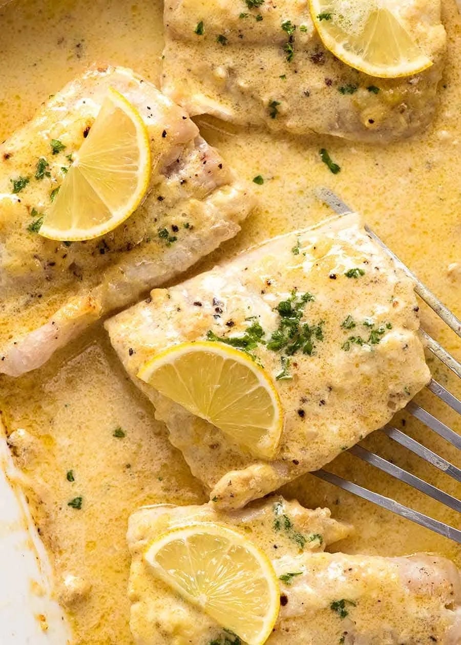 Fish fillets in creamy lemon sauce, garnished with lemon slices and parsley