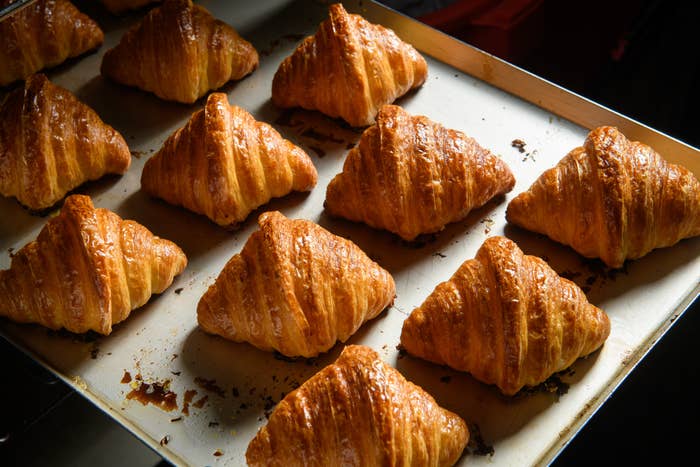 Freshly baked croissants on a baking tray, showing flaky, golden layers and crispy texture
