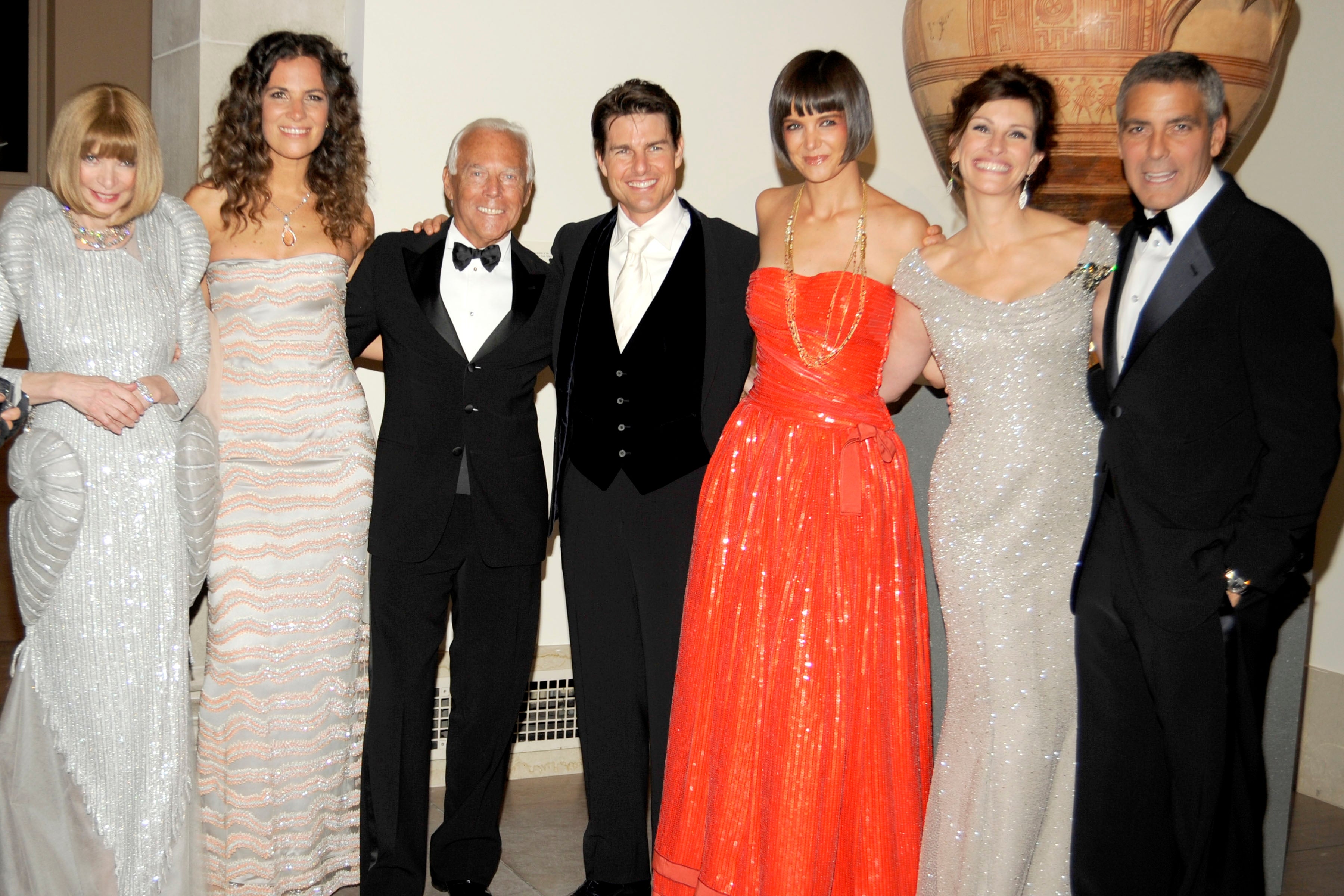 Group of 7  elegantly dressed people, including men successful  tuxedos and women successful  glamorous gowns, posing unneurotic  astatine  a ceremonial  event