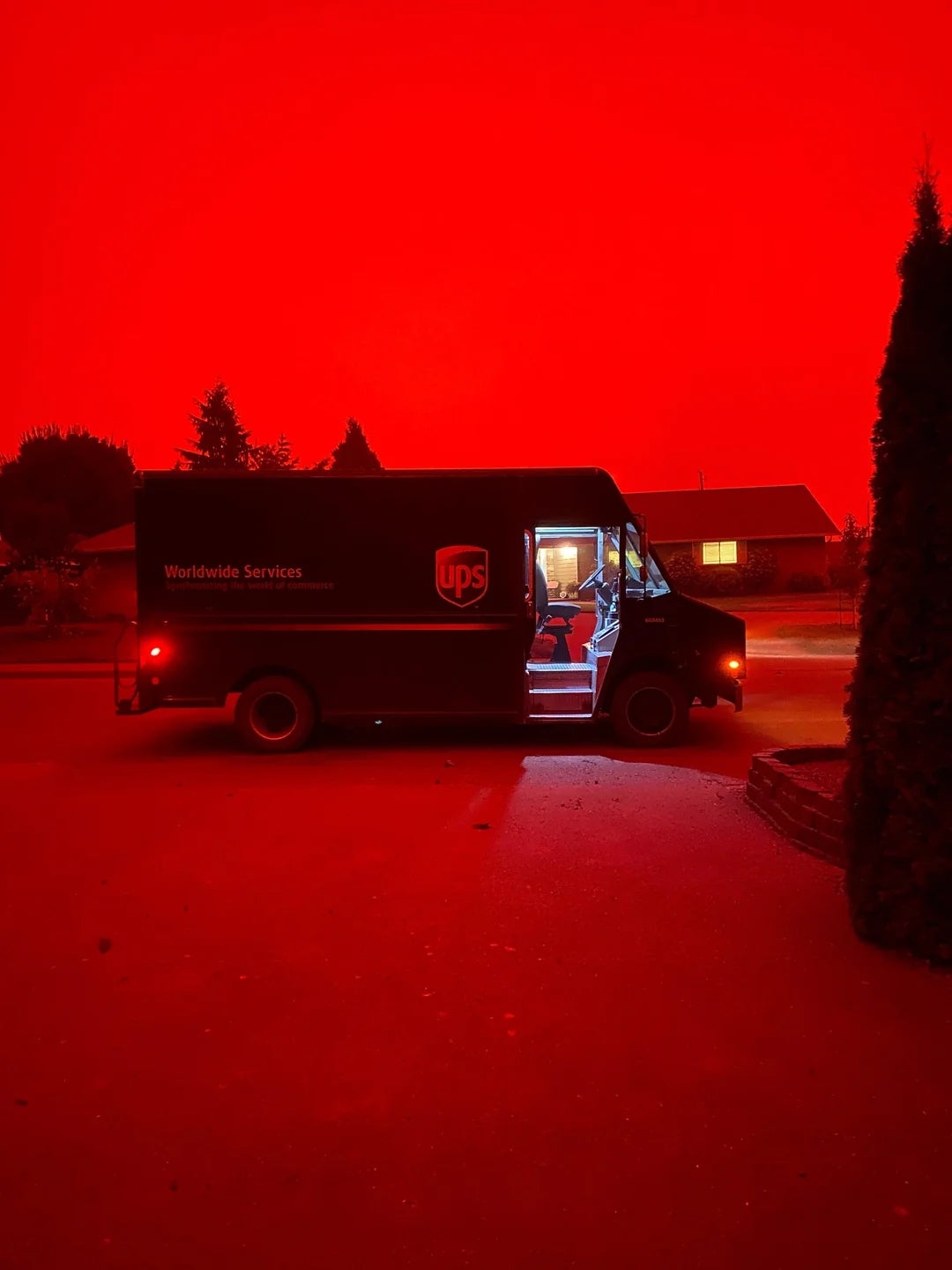 UPS motortruck  parked connected  a thoroughfare  with a idiosyncratic   wrong  nether  an aggravated  reddish  sky. The country   appears dramatically lit