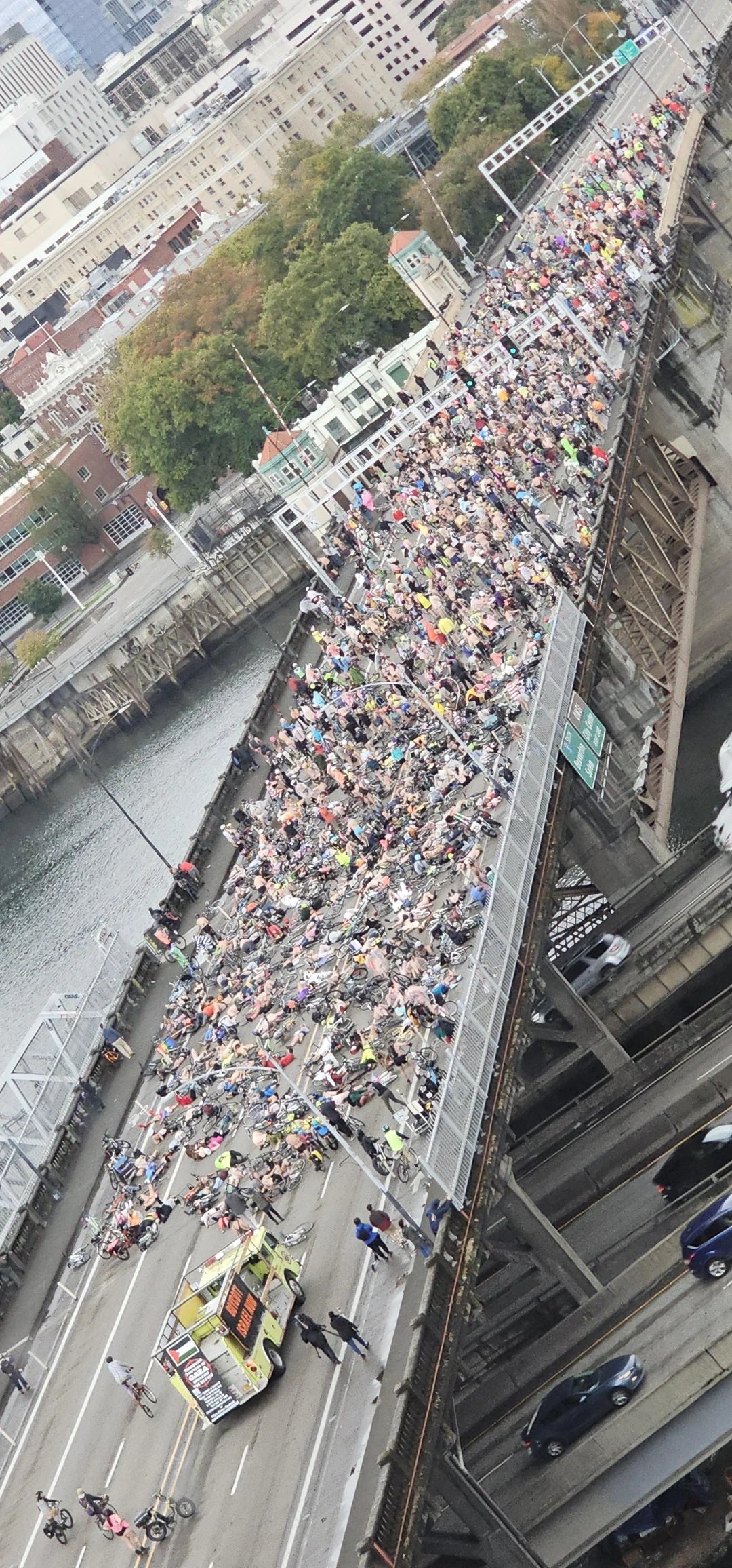 Large assemblage  gathered connected  a span  for a nationalist   objection  with signs; a colorful conveyance  and bikes are besides  present