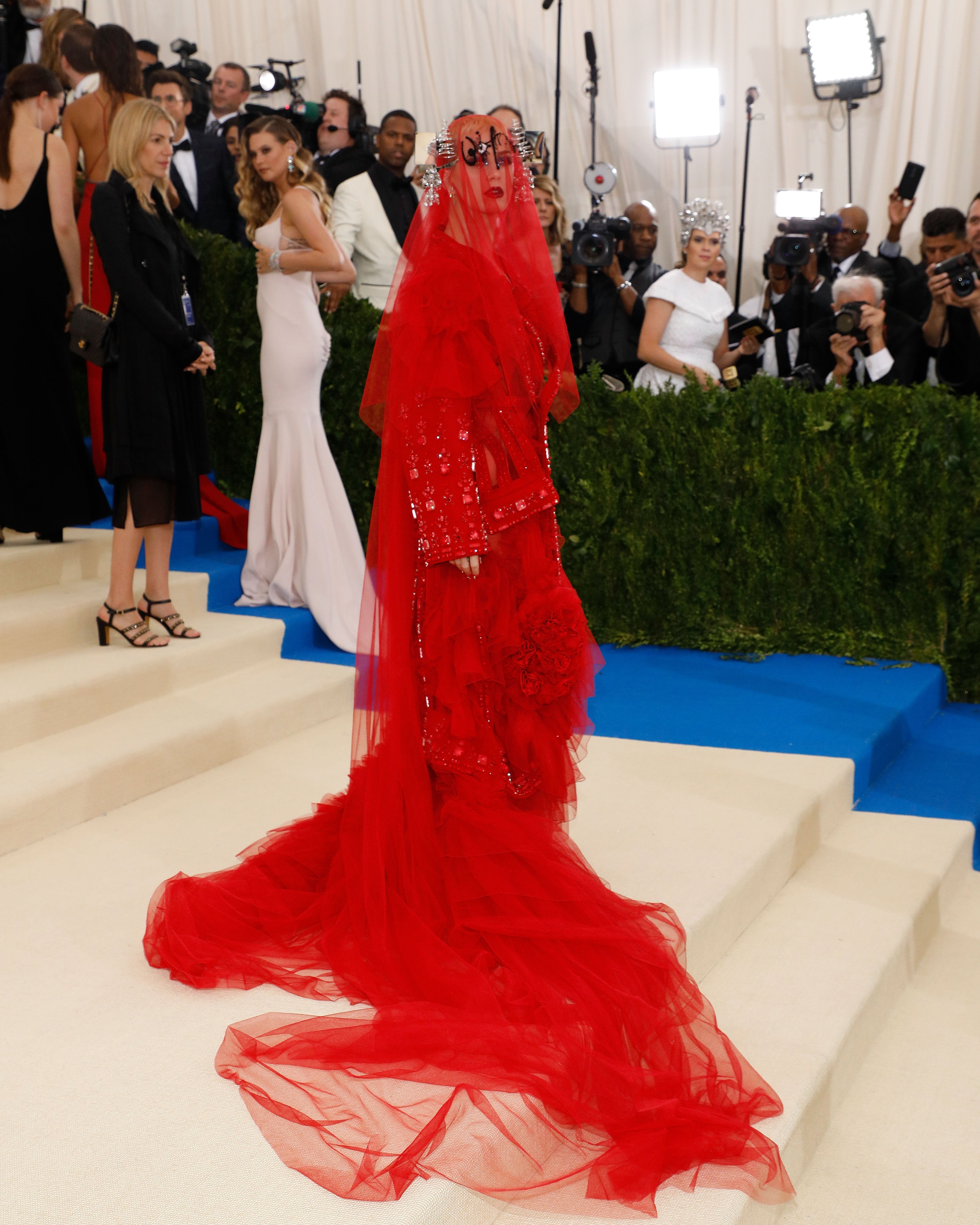 Celebrity successful  a dramatic, layered gown stands connected  a pick  carpet, surrounded by photographers and onlookers astatine  a ceremonial  event