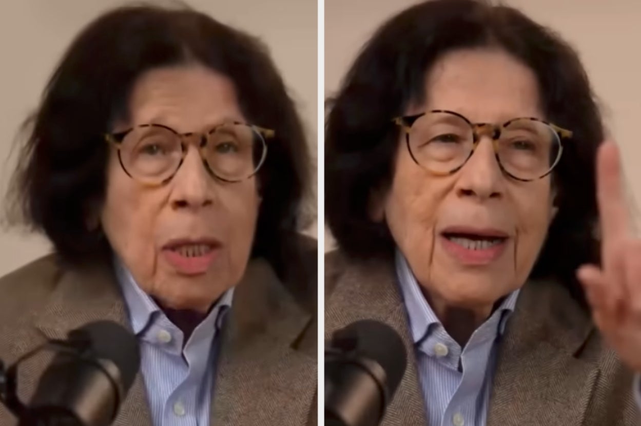 Person with glasses speaking into a microphone, wearing a blazer and shirt. Expressive gestures indicating discussion or debate