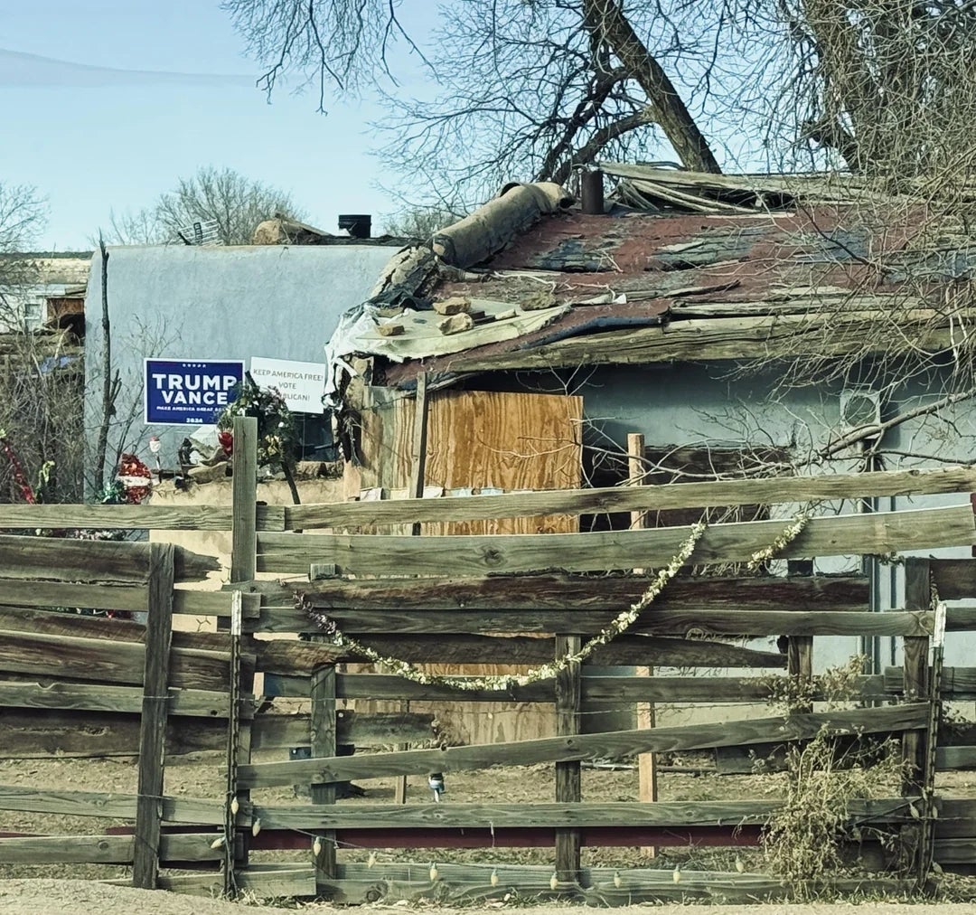 Weathered shed with a damaged roof, surrounded by a rustic fence; a Trump Vance run  motion   is disposable   successful  the background