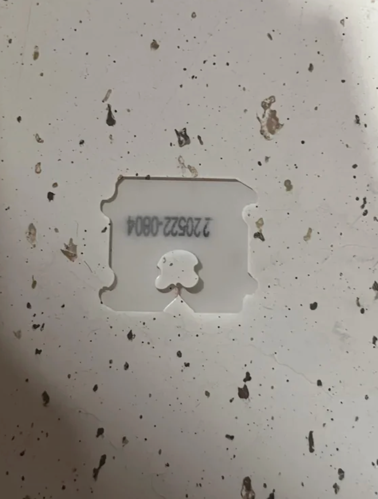 Plastic bread clip with numbers printed on it, placed on a speckled surface