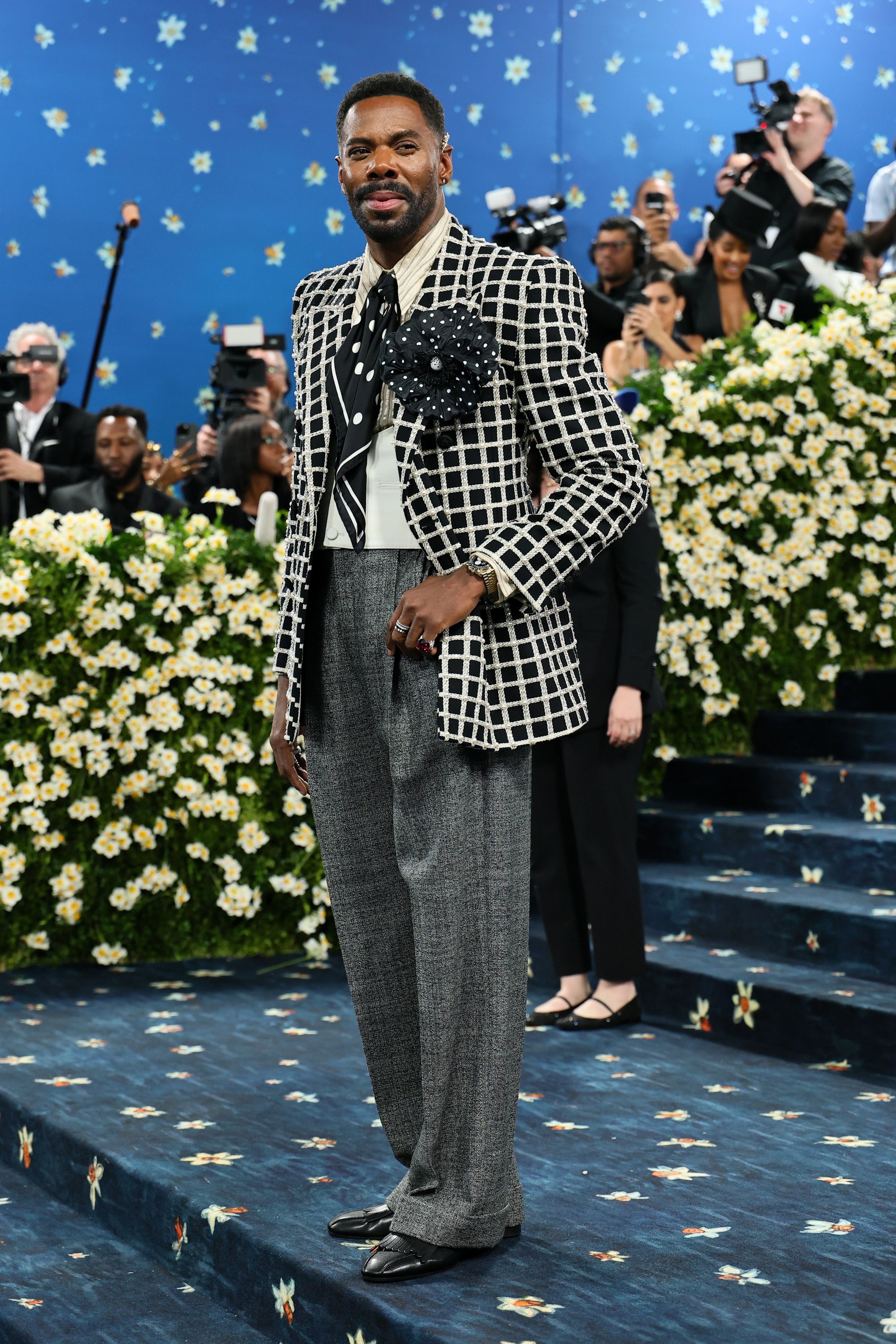 Man successful  a patterned suit   with a ample  polka-dotted necktie  and floral accessory connected  a star-themed carpet astatine  a personage  event