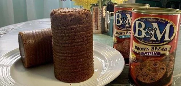 Canned brown bread, one whole and one sliced, on a plate next to B&amp;amp;M branded cans on a kitchen counter