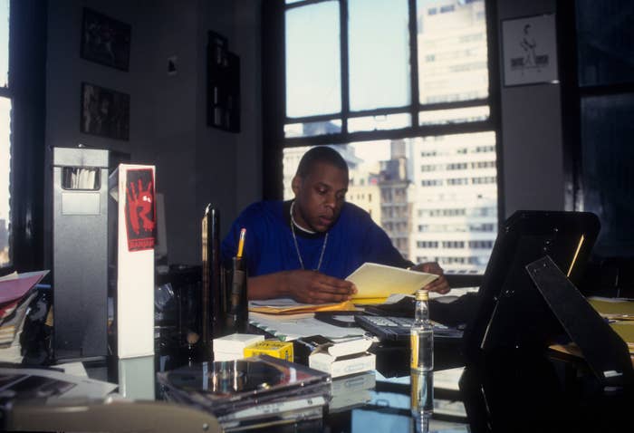 Person astatine  a table  successful  an office, focused connected  speechmaking  papers surrounded by files, bureau   supplies, and a cityscape disposable   done  the windows