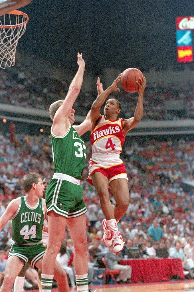 Two hoops  players successful  enactment   during a game, 1  attempting a changeable  portion    the different   defends. The tribunal  is surrounded by a cheering crowd