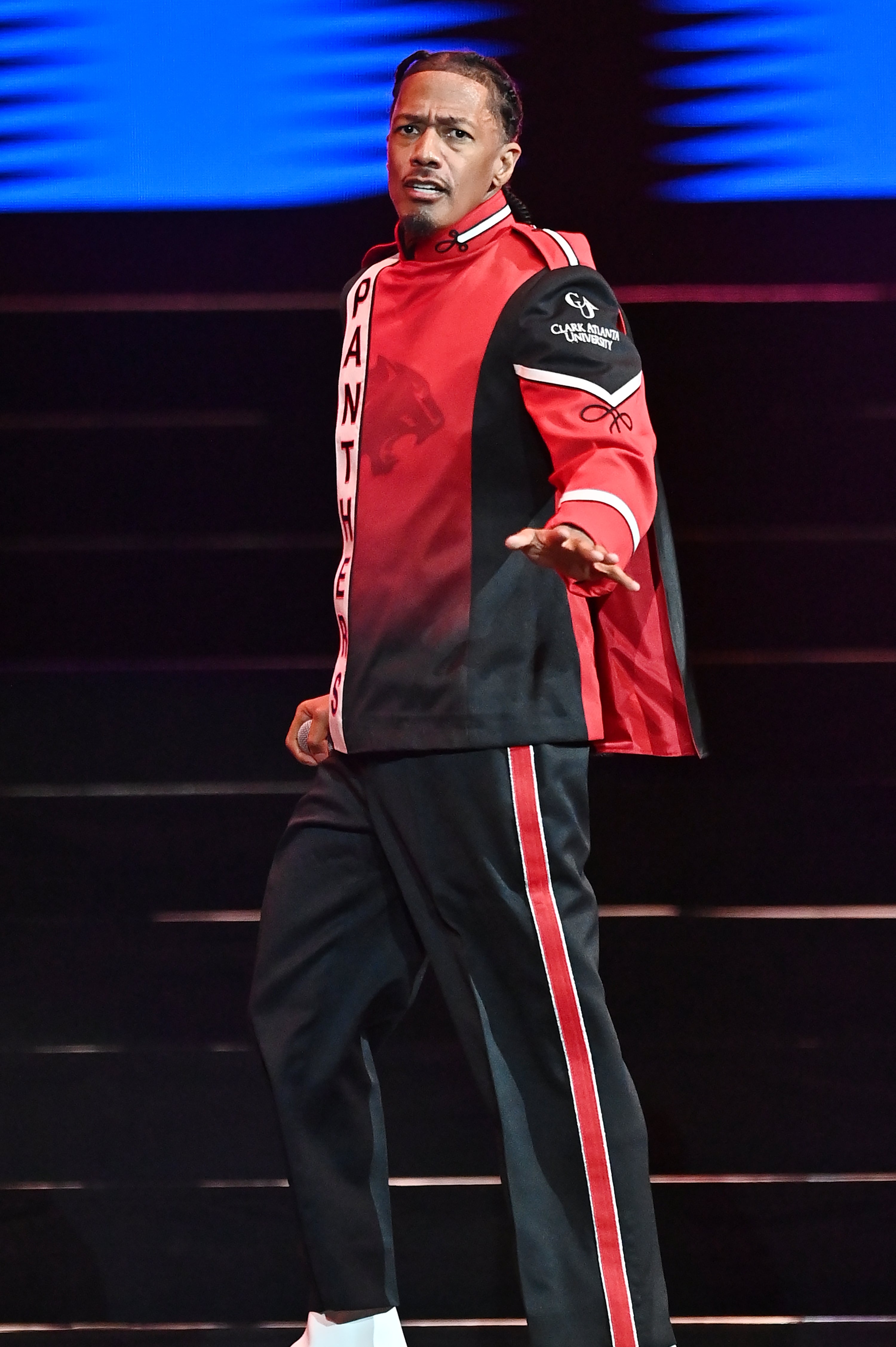 Nick Cannon successful  a marching band-themed outfit with "Panthers" substance   and a cape, posing connected  signifier    during an event