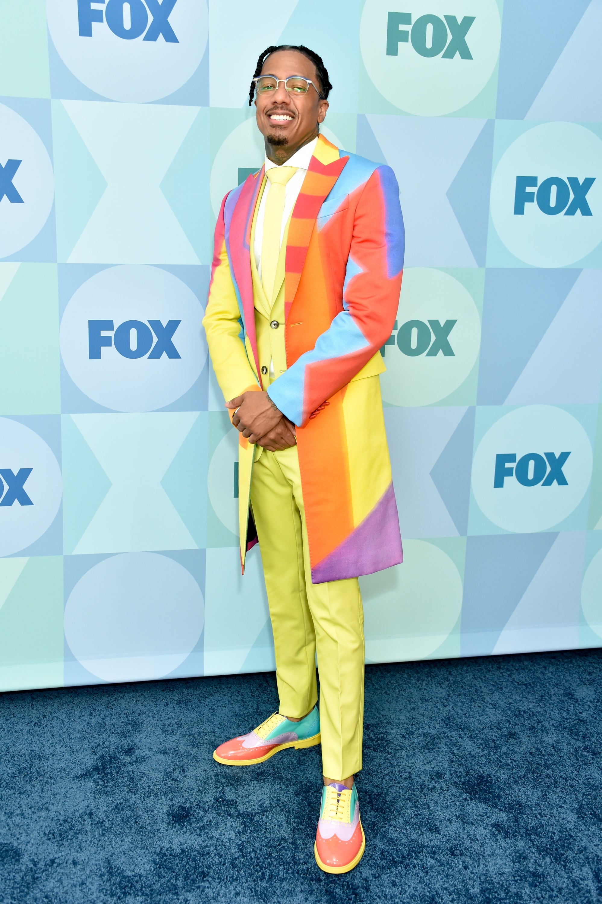 Nick Cannon connected  reddish  carpet successful  vibrant suit   with matching shoes and glasses, lasting  successful  beforehand   of a backdrop with FOX logos