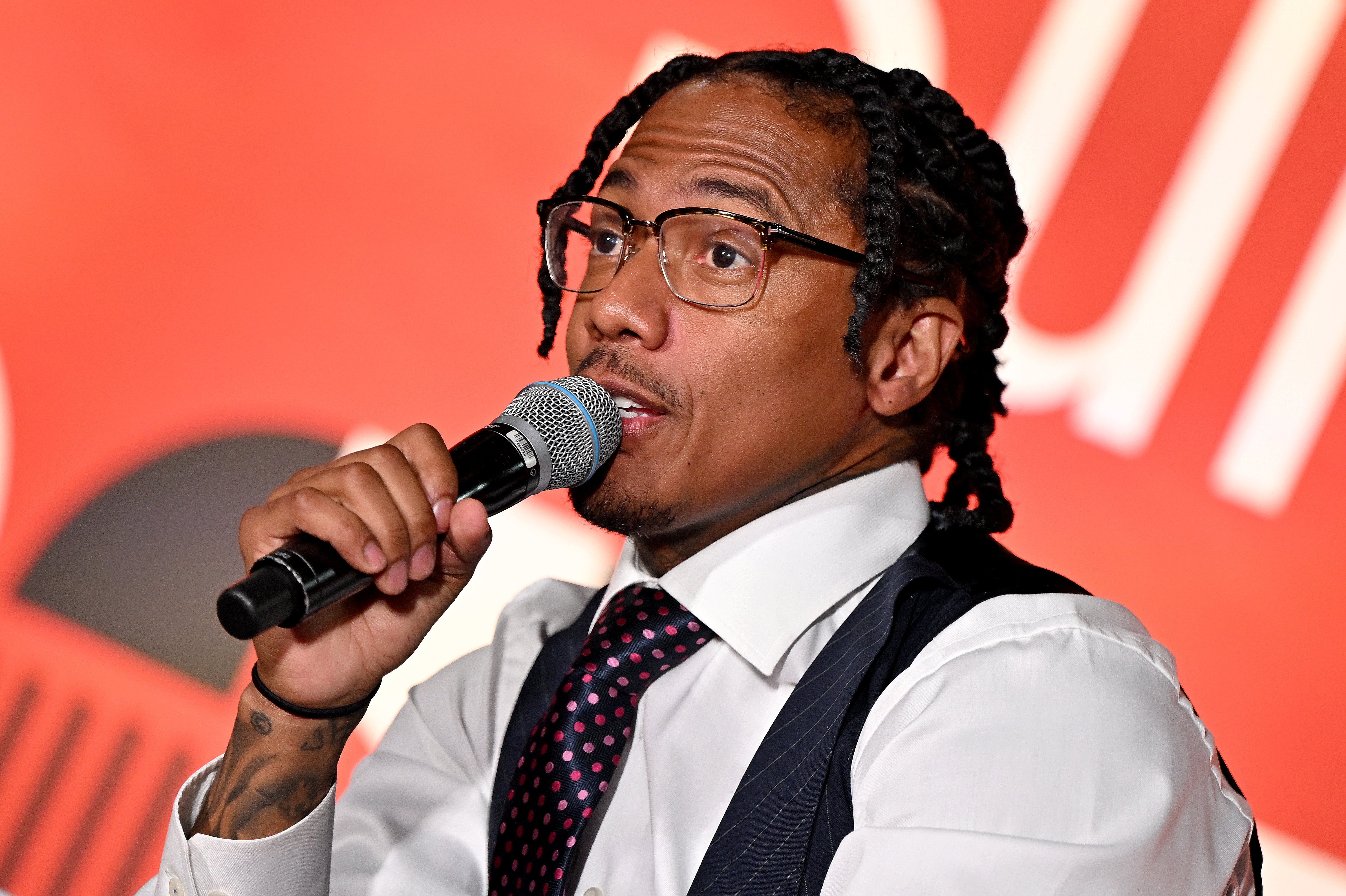 Nick Cannon successful  ceremonial  attire speaks into a microphone astatine  an event