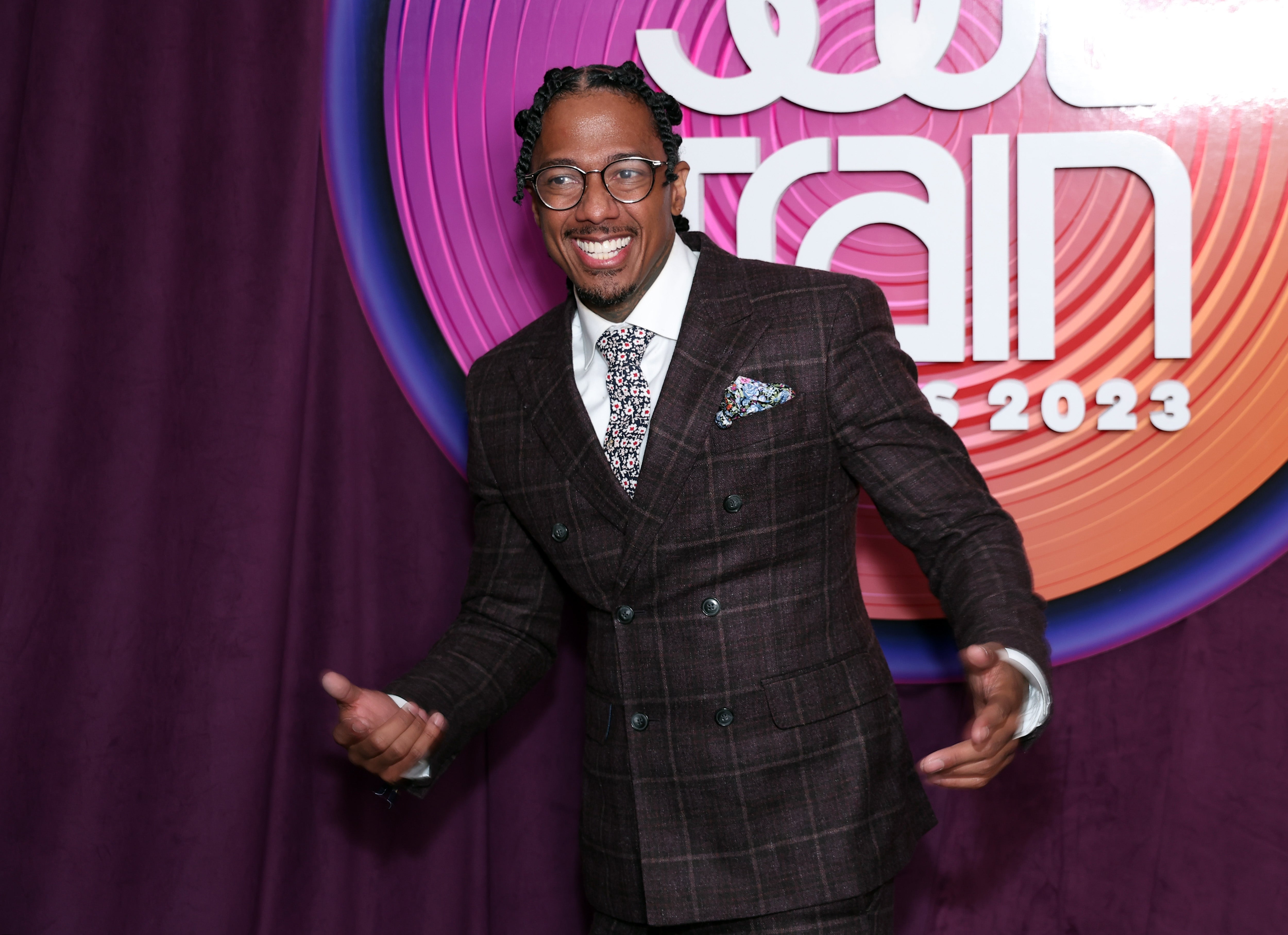 Nick Cannon successful  patterned suit   with a printed tie, smiling connected  a reddish  carpet astatine  an event
